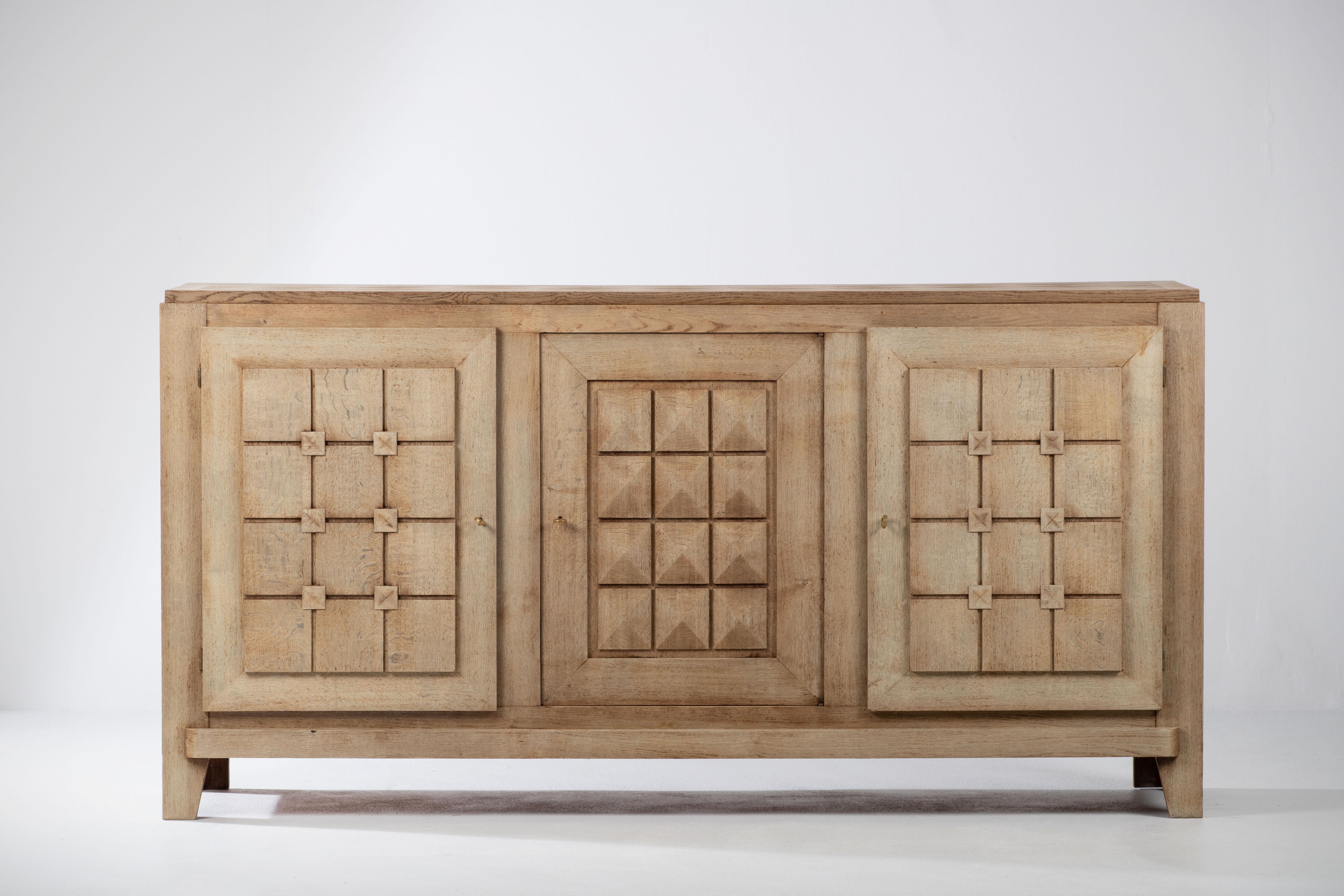 Large Credenza, solid oak, France, attributed to Charles Dudouyt, 1940s.
Large Art Deco Brutalist sideboard. 
The credenza consists of three storage facilities and covered with very detailed designed doors. 
The refined wooden structures on the