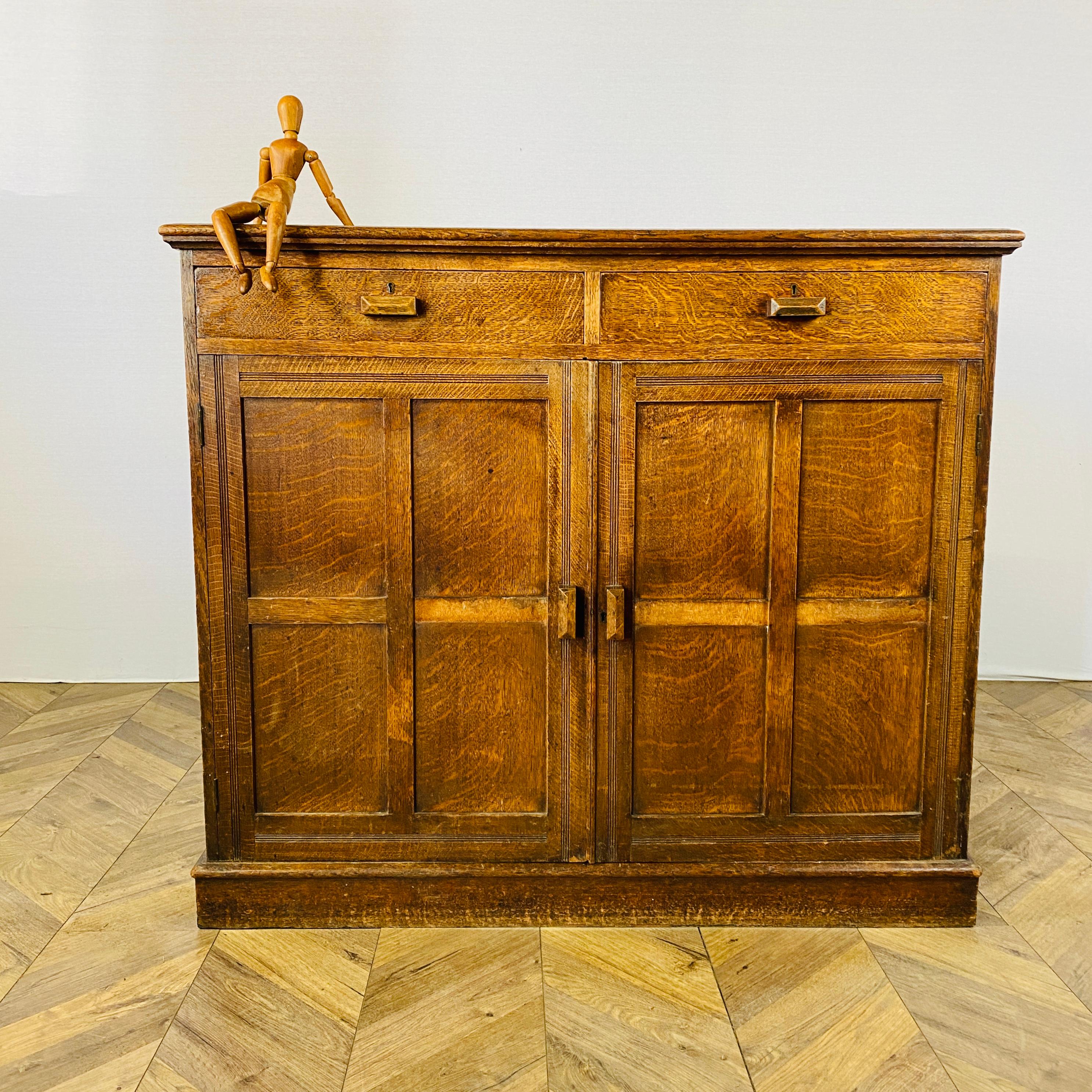A beautifully large solid oak English sideboard / cabinet, circa 1920s.

The cabinet boasts 2 drawers over a 2-door cupboard with fixed shelves (one shelf is not original) and rich worn patina.

The cabinet is extremely heavy and well built but