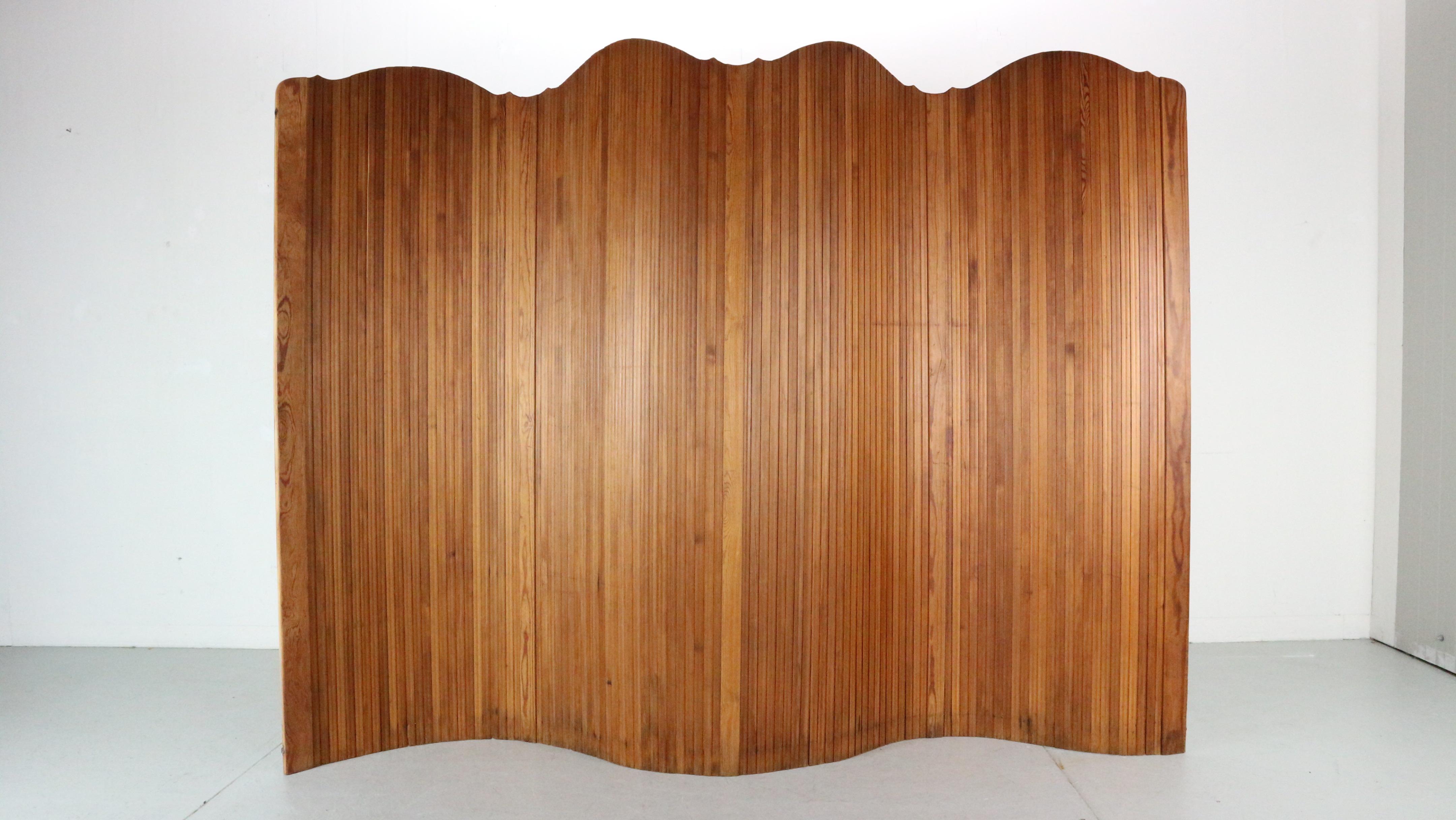 Large 1920s Tambour screen by the French manufacturer S.N.S.A. Made in stained pitchpine.
Its flexible structure allows it to stand freely and shape curves, perfect for a dressing room or as a room divider, can also be rolled up for easy