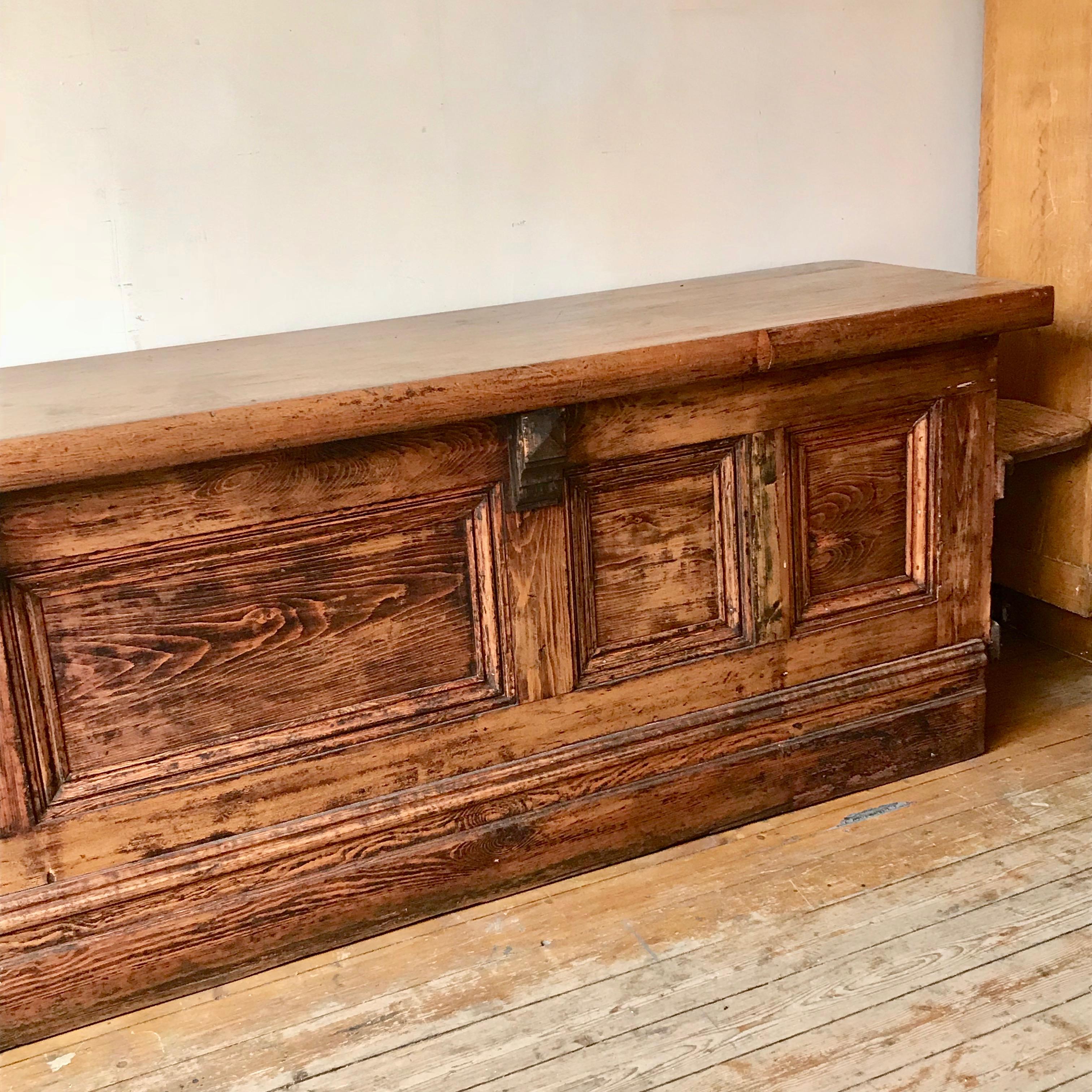 Large solid pine Victorian shop counter made in 1897 and salvaged from it's original shop in Stockport, UK. The right hand side features a fold out seat. It has been sympathetically restored by removing the worn varnish removed and then a waxed