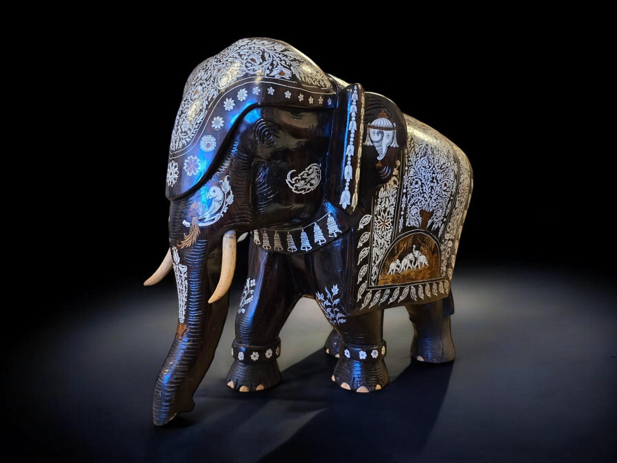 Ti presentiamo un grande elefante scolpito in legno massiccio proveniente dall'India e risalente ai primi anni del 1900. Questo pezzo eccezionale è realizzato con un legno denso e scuro simile all'ebano ed è impreziosito da intarsi in avorio. Questo