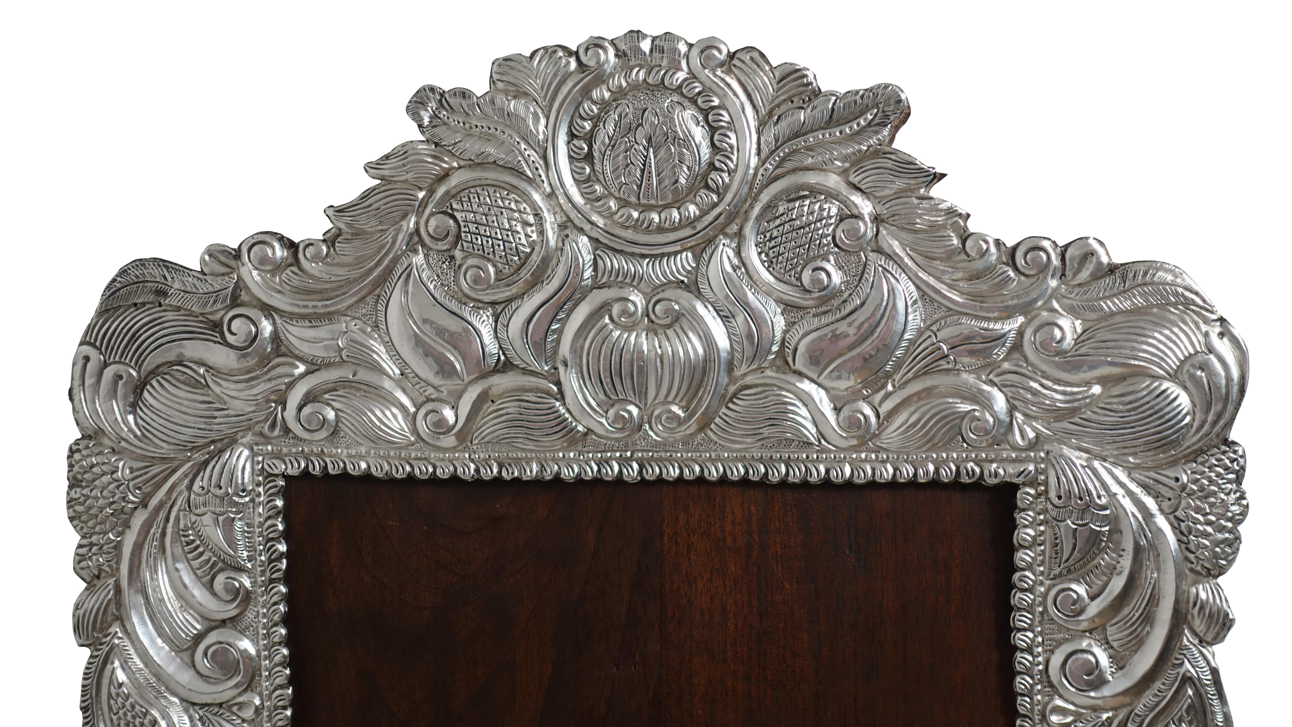 An usually large Spanish Colonial silver frame (possibly originally for a religious saint) with a mahogany back. Having a wonderful mix of European and Colonial design of C-scrolls, sun flowers and leaves. Unmarked but definitely silver. South