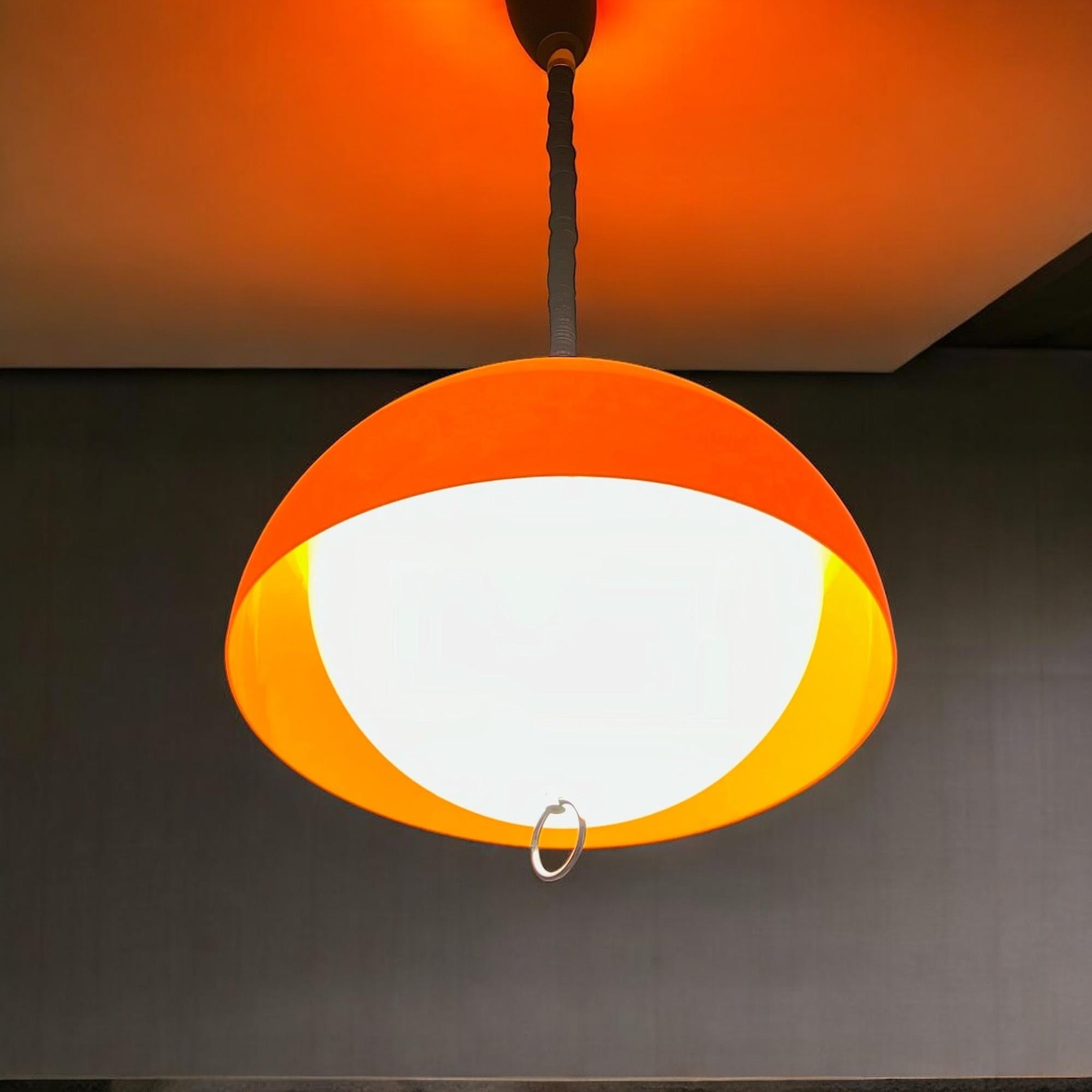 Striking large space age lamp in vibrant orange and white plastic, reminiscent of the iconic 70s creations by Harvey Guzzini. This eye-catching chandelier, with its bold colors and sleek shape, is sure to bring a touch of vintage flair and