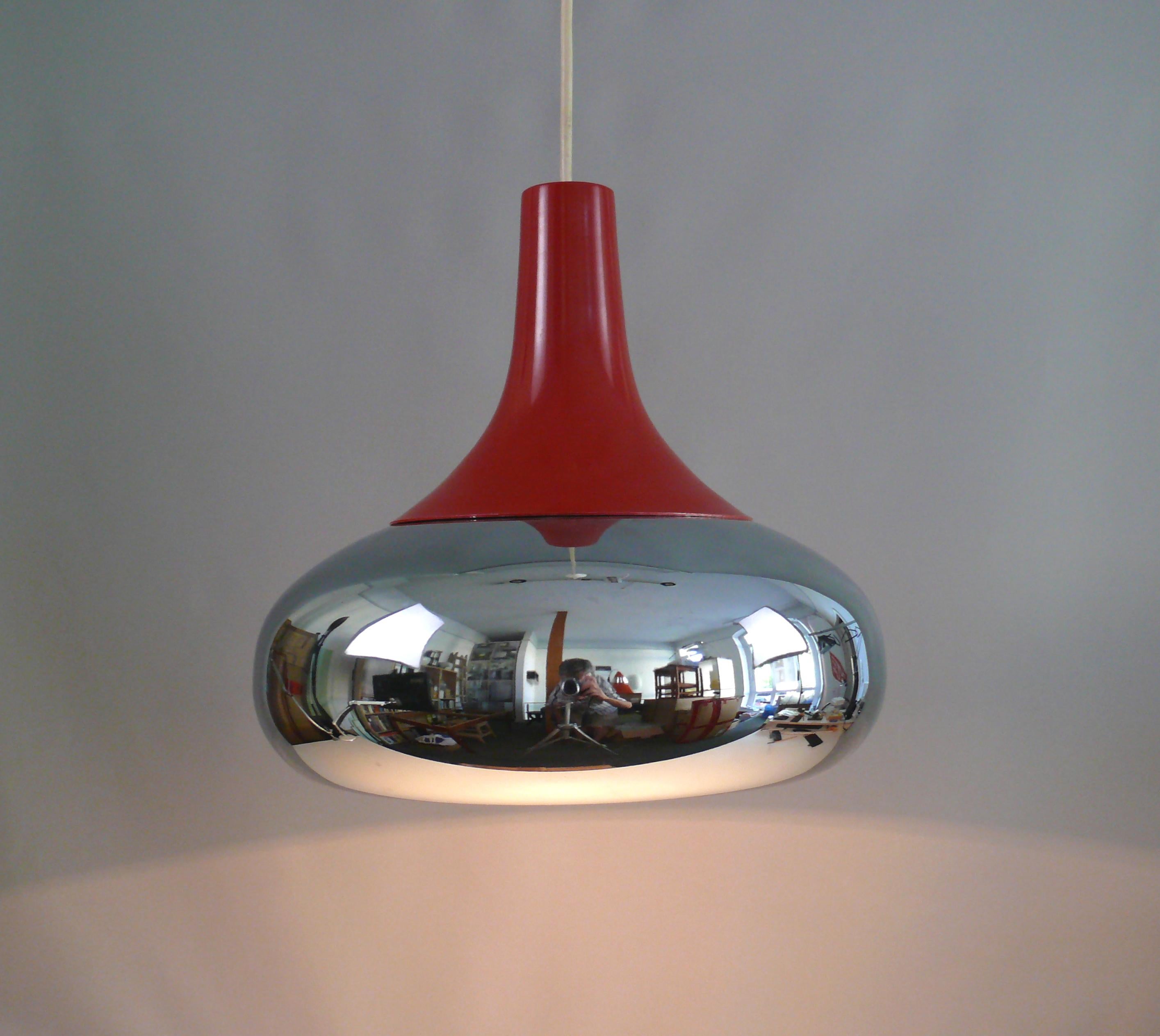 1960s chrome pendant light with red painted metal cover, no label left.

Space age design: The lamp has a typical 1960s design with a UFO-shaped, chrome-plated shade. The shade is coated in white on the inside. The light only shines downwards. The