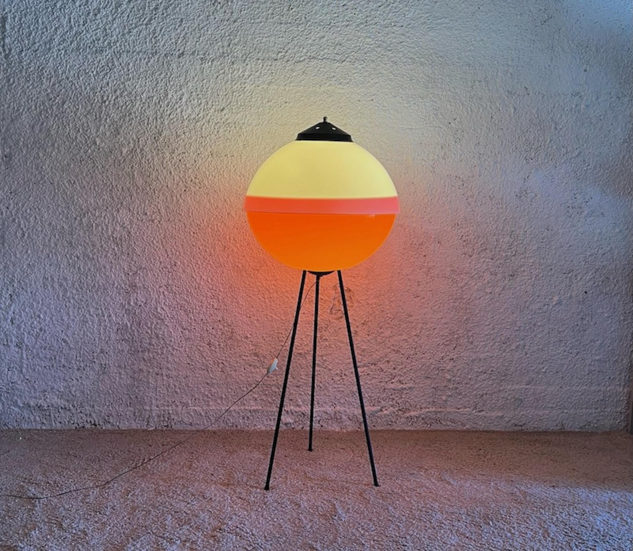 Unique and impressive space age UFO floor lamp with an awesome flying saucer shape made in Italy in the 60s.

The large acrylic lampshade is made of two pieces with the timeless white / orange color match. The tripod made of slender black metal legs