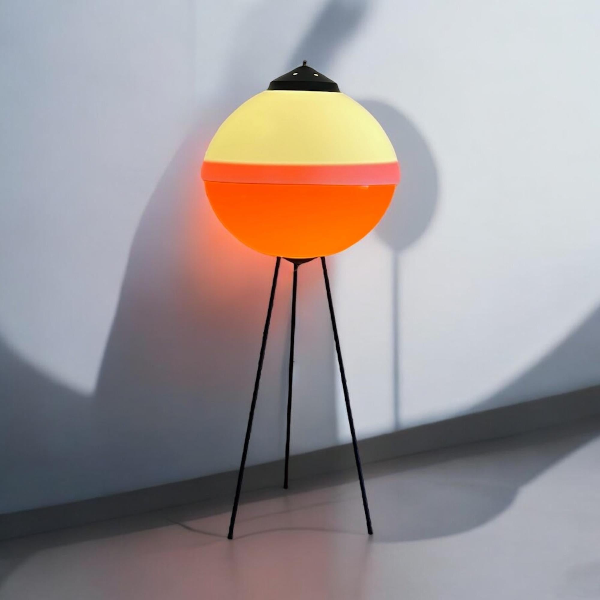 Unique and impressive space age UFO floor lamp with an awesome flying saucer shape made in Italy in the 60s.

The large acrylic lampshade is made of two pieces with the timeless white / orange color match. The tripod made of slender black metal legs