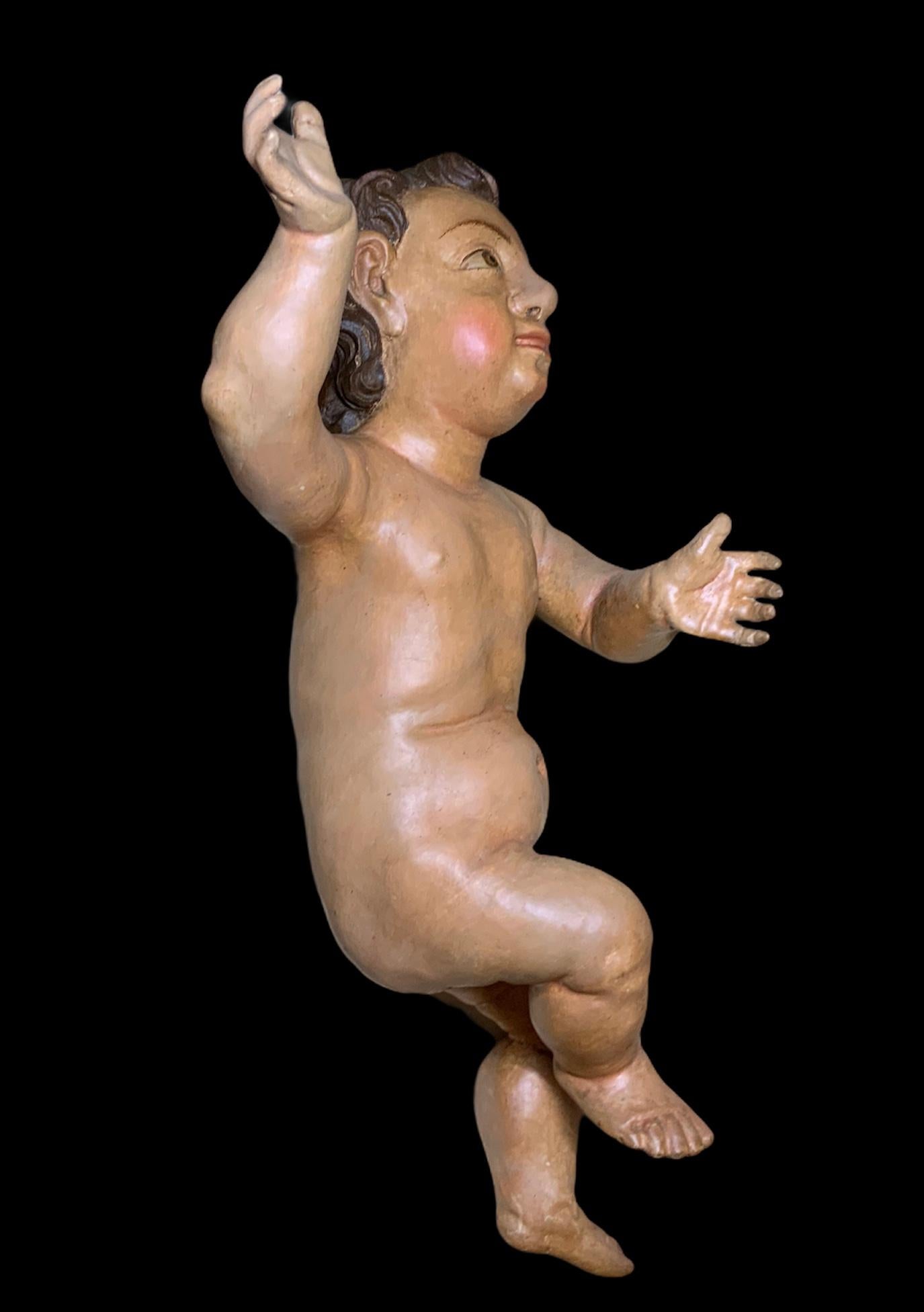 Il s'agit d'un ancien bébé Jésus en bois sculpté et peint à la main par des Espagnols. Il a de grands yeux expressifs et des sourcils peints à la main. Sa chevelure abondante est brune et bouclée. Sa main droite est levée en position de bénédiction