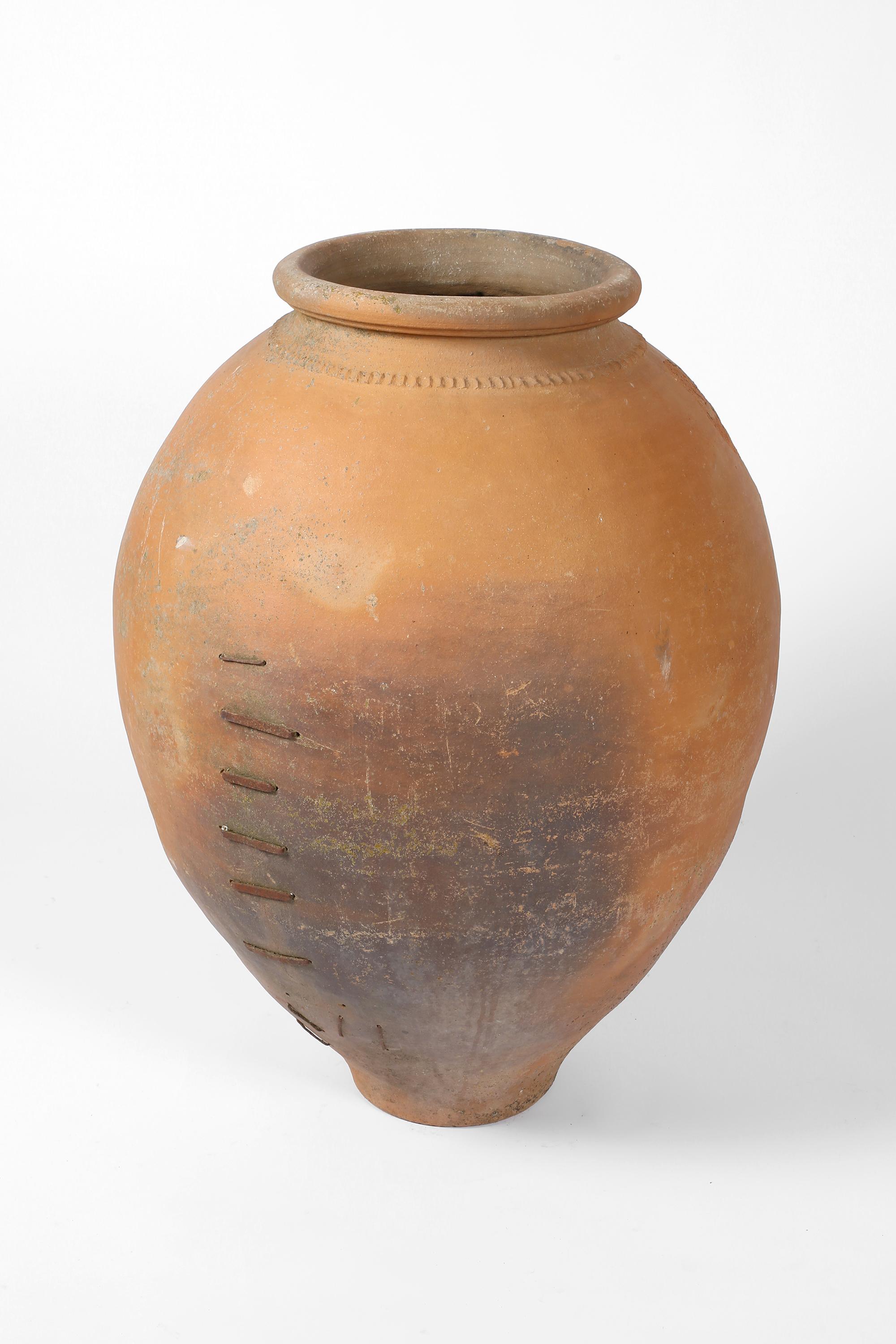 A very large and heavily patinated hand-thrown terracotta wine jar, with characterful iron staple repair to a hairline crack. From the province of Seville in Andalusia. Spanish, circa 1780.

H101 cm