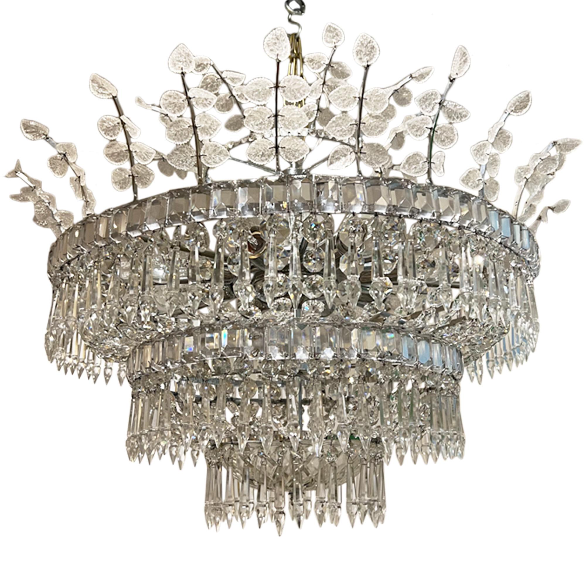 This decorative chandelier was made in Spain in the 1960s in the Baguès style. 

The light is made up of a number of different components - glass leaves, crystal drops and lozenges with a lovely glass dome at the bottom. Take a look at all our