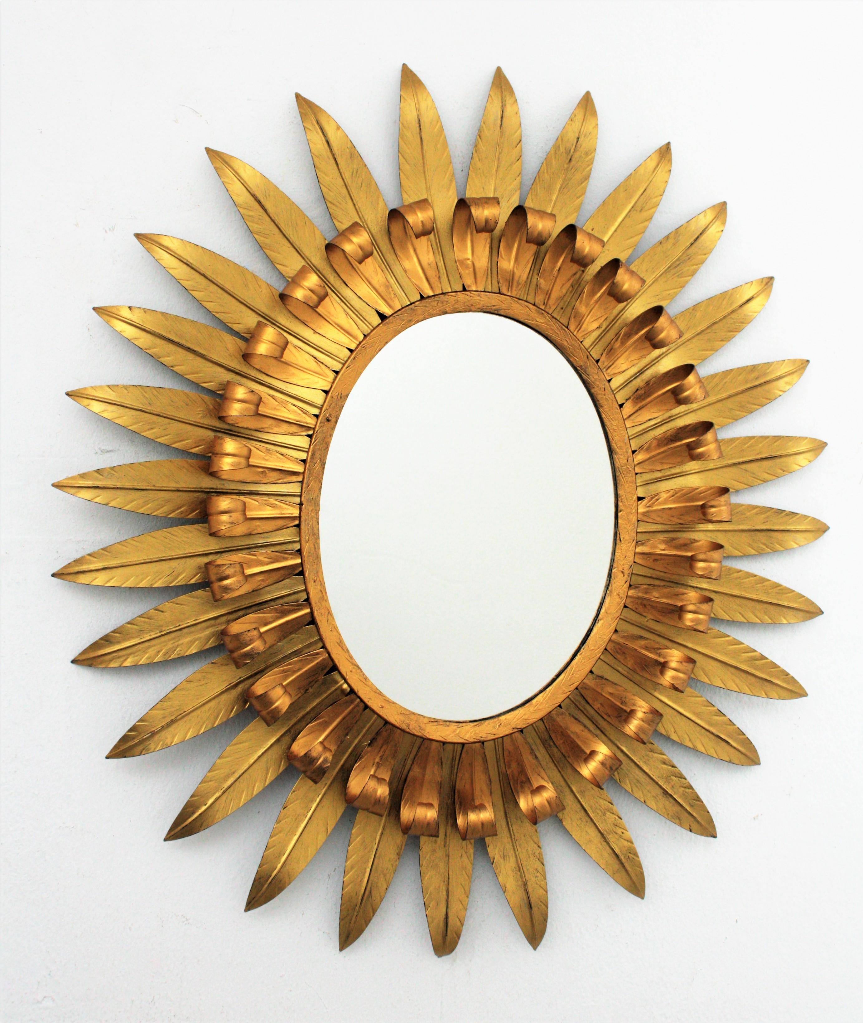 Spanish gilt iron Mid-Century Modern eyelash oval sunburst mirror with gilt patina in two golden tones. Spain, 1960s. 
This mirror has two layers of beams, one of them with eyelash shape. The bicolor tones highlight the beauty of this sunburst