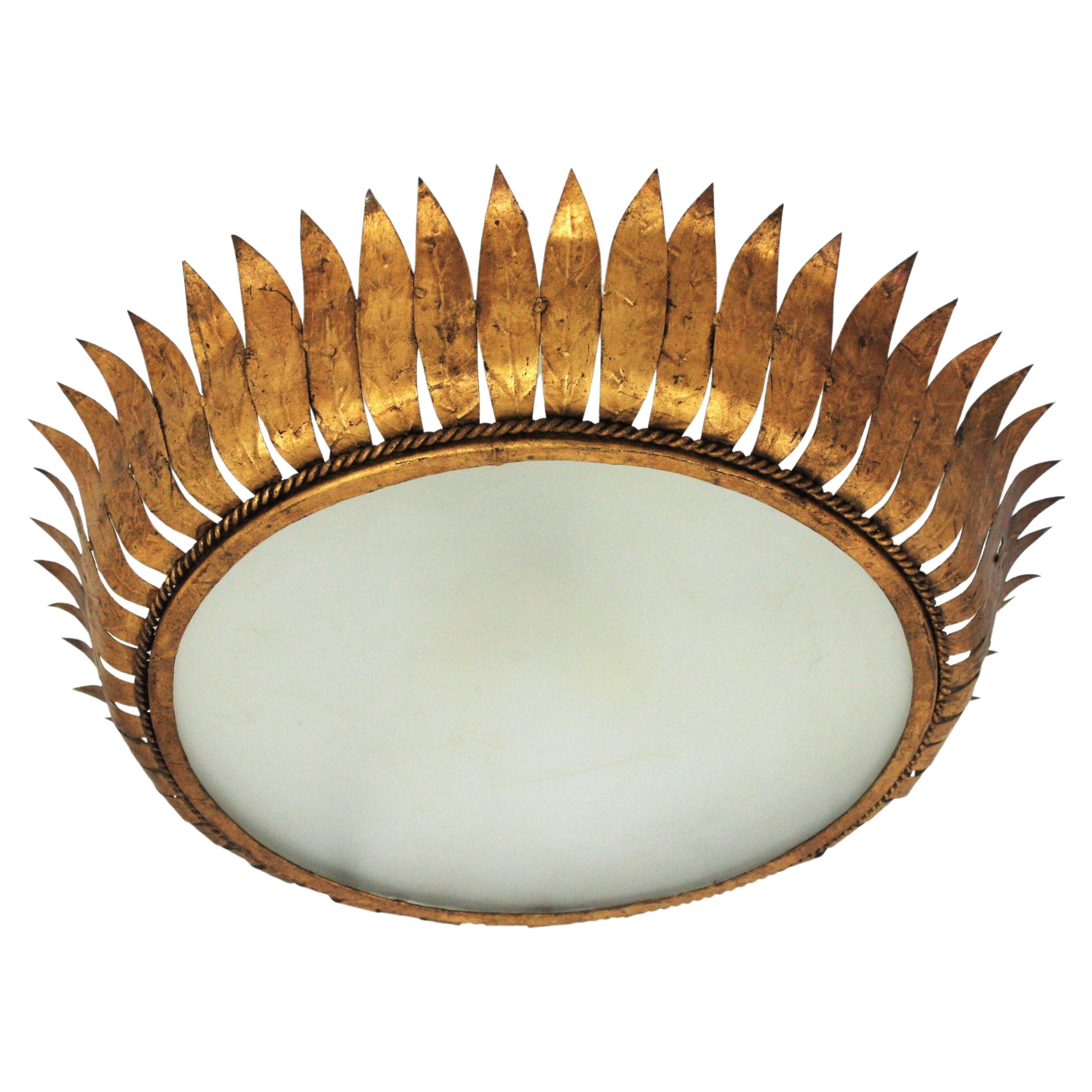 Large spanish gilt Metal crown sunburst leafed light fixture with Frosted Glass, Spain, 1950s.
Mid-Century Modern gilt iron crown sunburst flush mount or pendant with leaf motifs surrounding a central frosted glass diffuser. Handcrafted in hammered