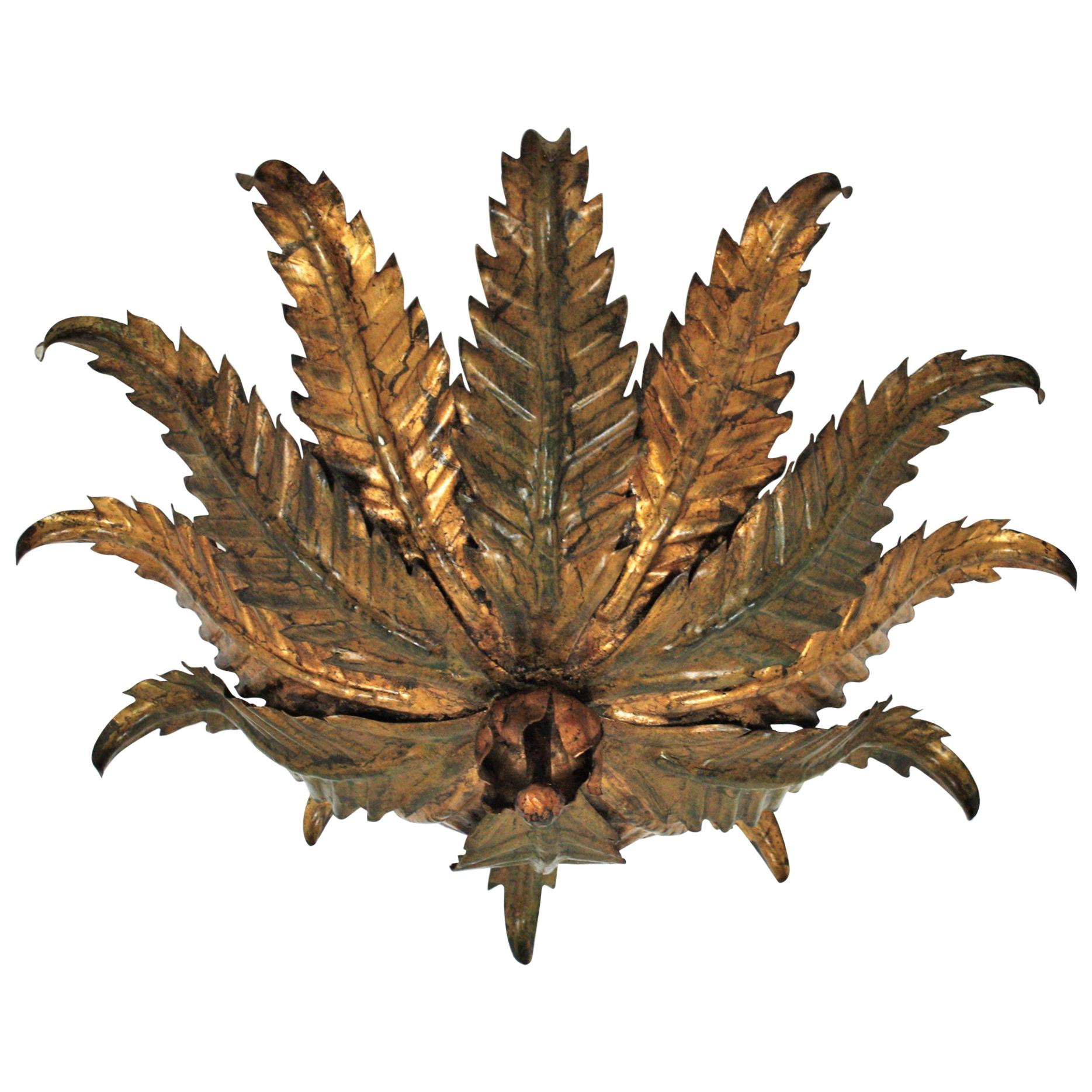 Spanish Sunburst Floral flush mount in two-tone green and gilt wrought iron, 1950s
This eye-catching hand-hammered gilt iron floral ceiling light fixture has gilded leaves alternating with other with green accents.
The canopy with flower shape and