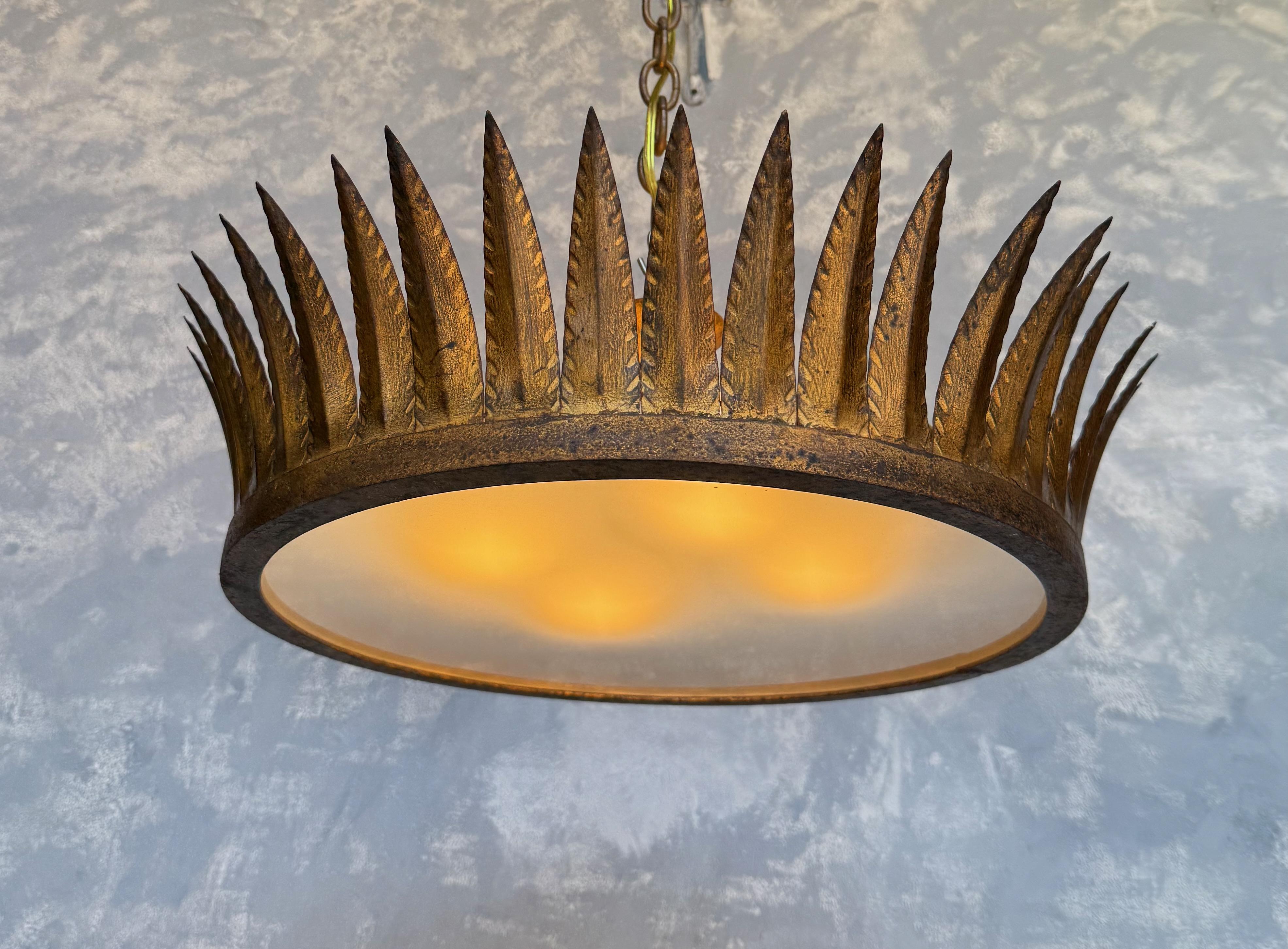 
A striking vintage Spanish flush mount ceiling fixture , circa 1950s, crafted in richly patinated gilt metal. The circular frame is crowned with a series of upward-pointing, hand-formed leaves, creating a bold and sculptural silhouette. An
