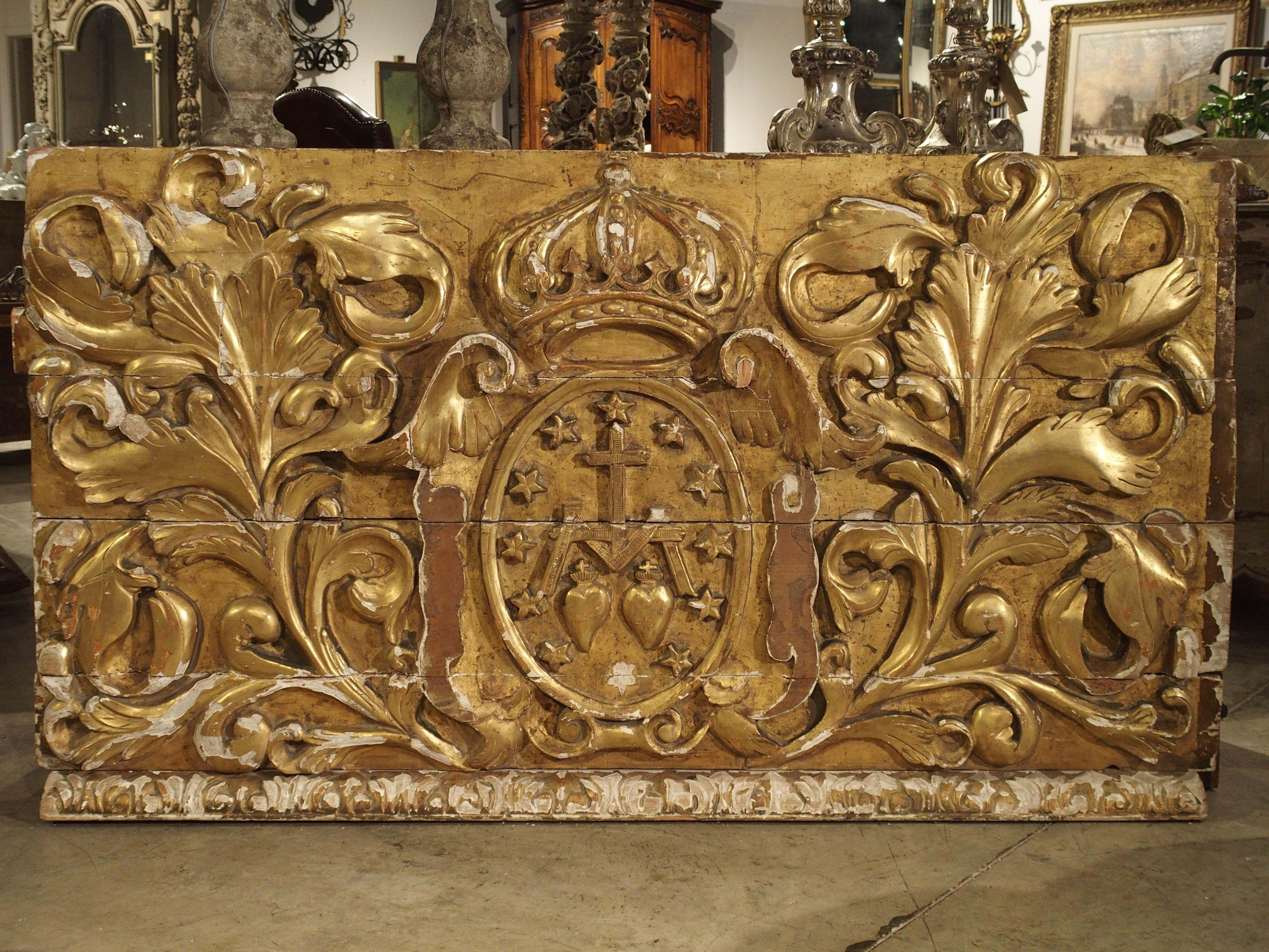 From Spain, this magnificent parcel-gilt panel overdoor dates to the middle of the 19th century. On either side of the central medallion are two large foliate carvings. The top is a crown upheld by two wings on either side of the escutcheon. The