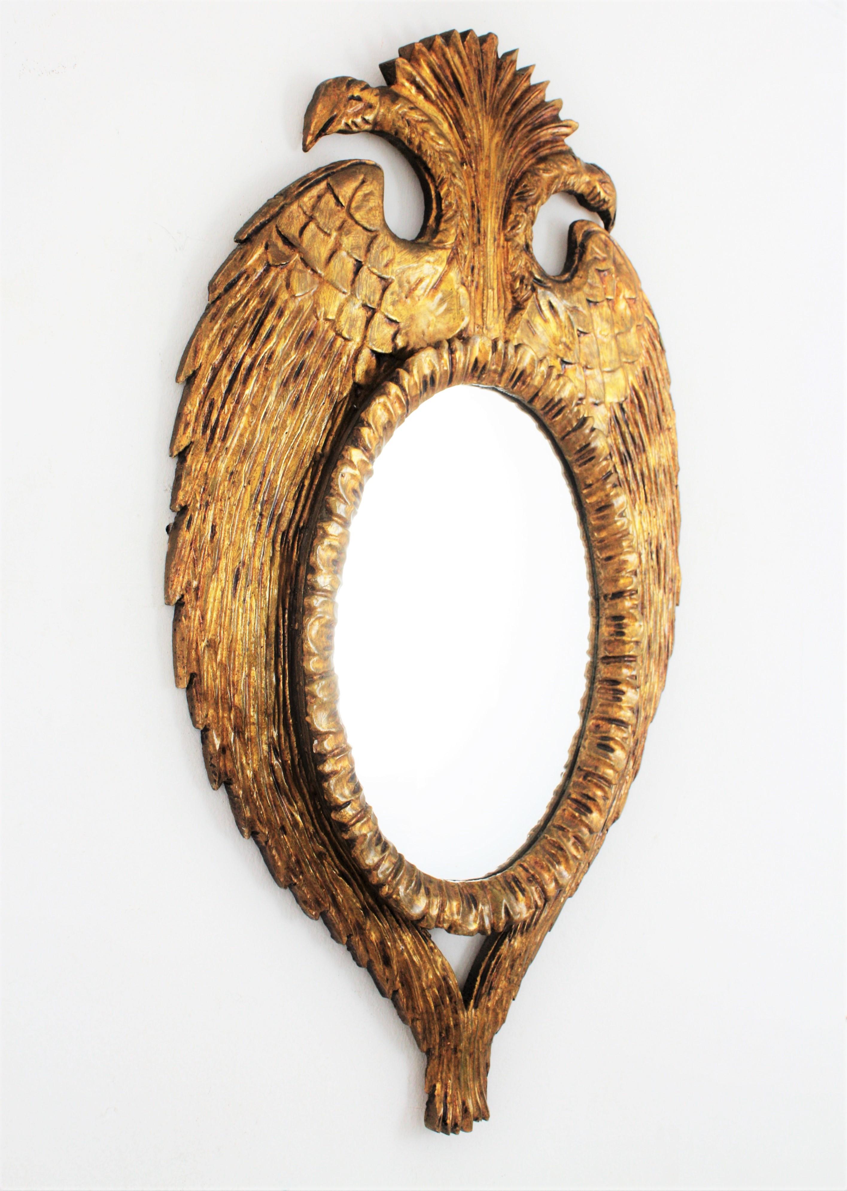 Magnificent carved giltwood double headed bird shaped frame with an scalloped pattern surrounding an oval mirror, Spain, 1950s-1960s.
Unusual frame with a highly decorative double headed eagle with symmetric wings and tails holding the central oval