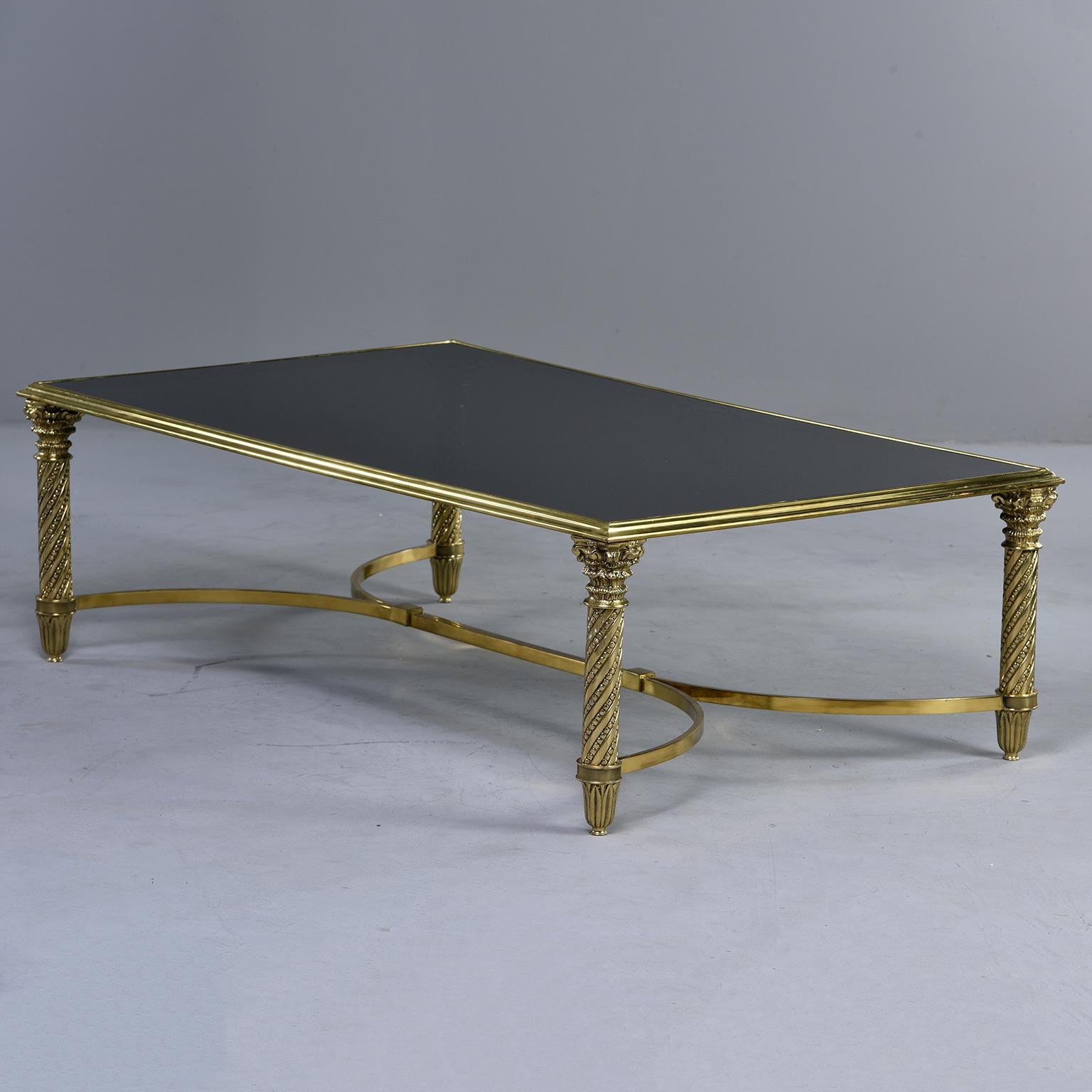 Spanish coffee or cocktail table has a brass base with decorative twisted legs and black glass top, circa 1960s. Unknown maker.