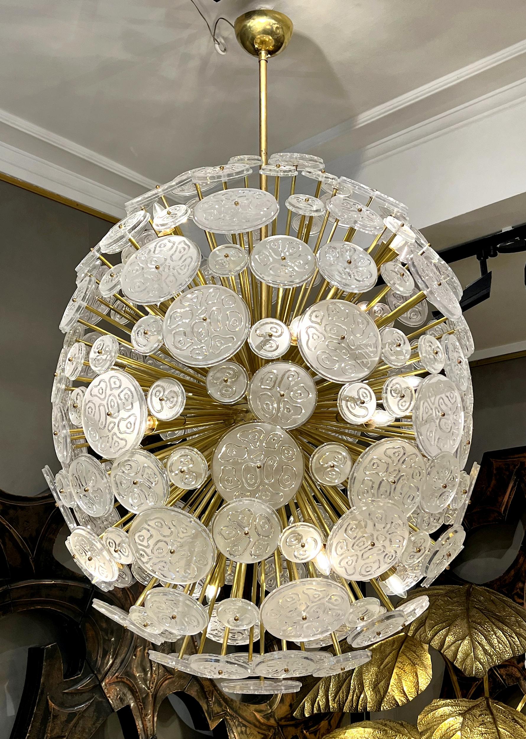 Large « sputnik » chandelier featuring numerous brass rods fixed to a sphere and supporting round plates of etched and sandblasted glass of various sizes. Sixteen bulbs. The supension rod can be shorted or changed for a longer one.
Height: 170 cm