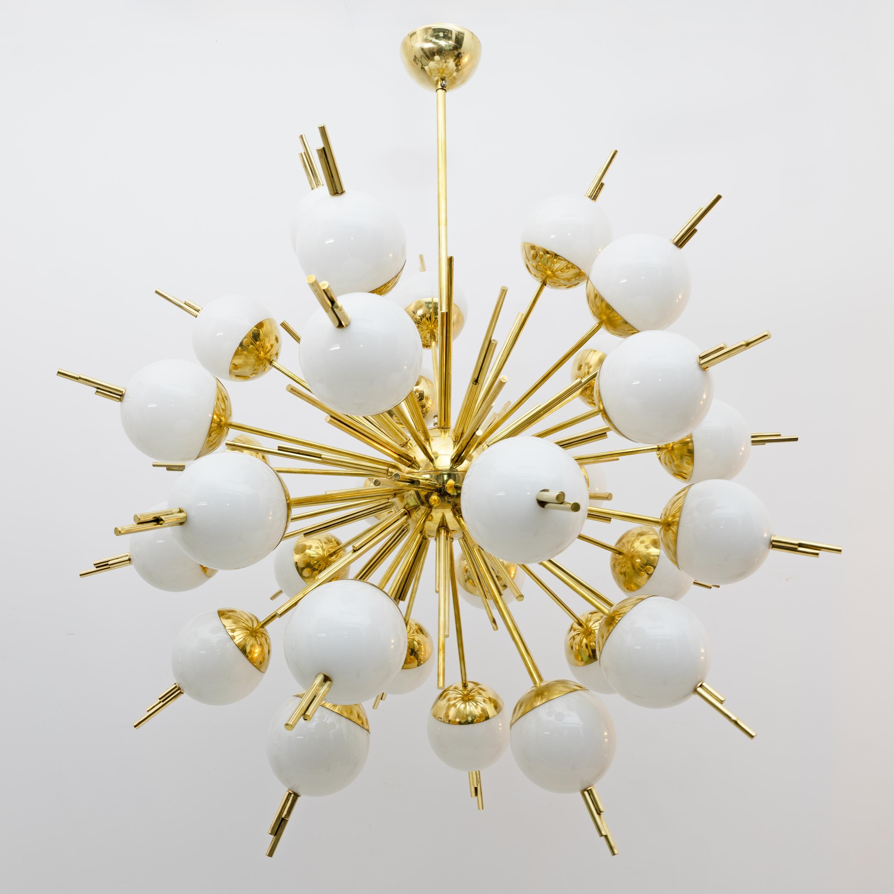 Lustre moderne Sputnik au design élégant et saisissant. Il se compose d'une structure centrale en laiton à partir de laquelle rayonnent de nombreux bras, créant une forme semblable à celle d'une explosion ou d'un rayon de soleil. À l'extrémité de