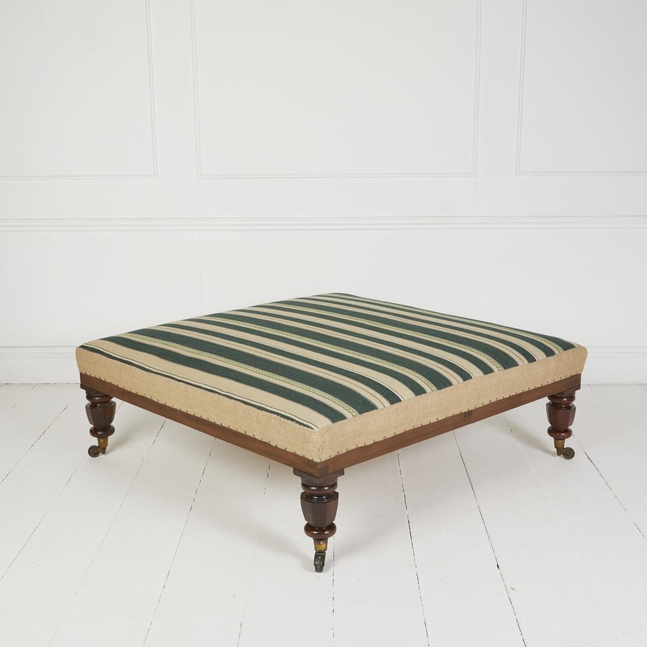Coach-built ottoman stool covered in heavy green stripe fabric,
Traditionally upholstered using only environmentally friendly natural products covered in heavy striped fabric with a hand stitched jute border.
Standing on English antique mahogany