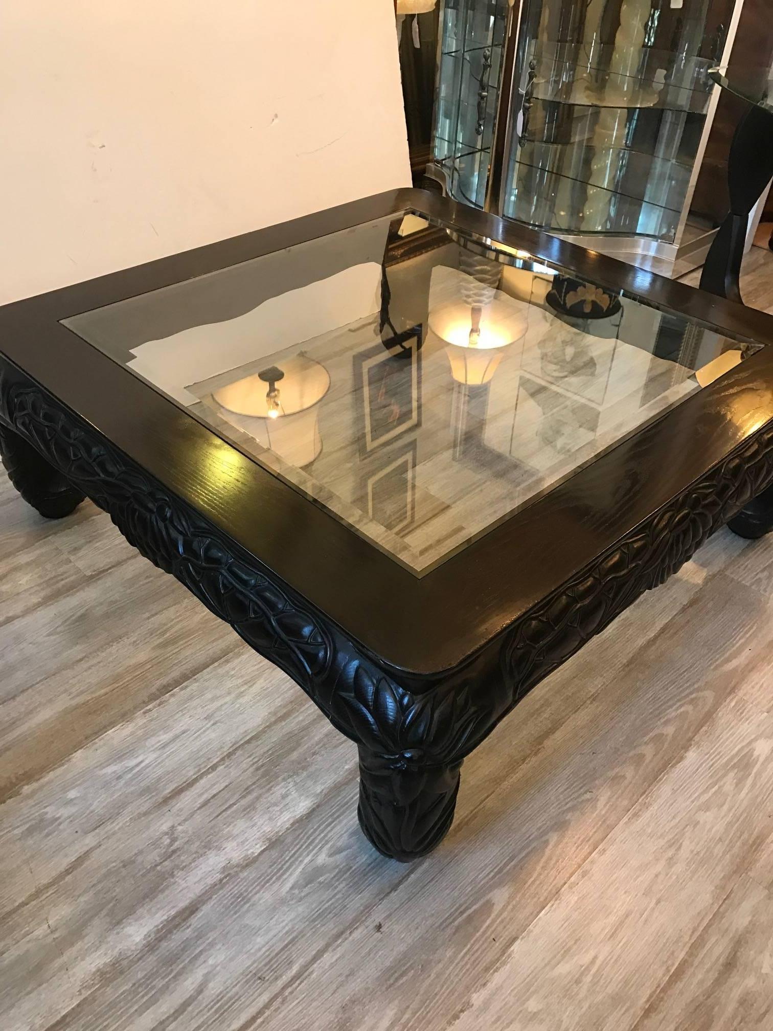 Hand carved dark wood and beveled glass cocktail table in an Asian style. The carved apron and turned in legs with the carving all-over. The glass top fits into the upper frame. The glass has a minor sliver chip about 2 inches long less than 1/4