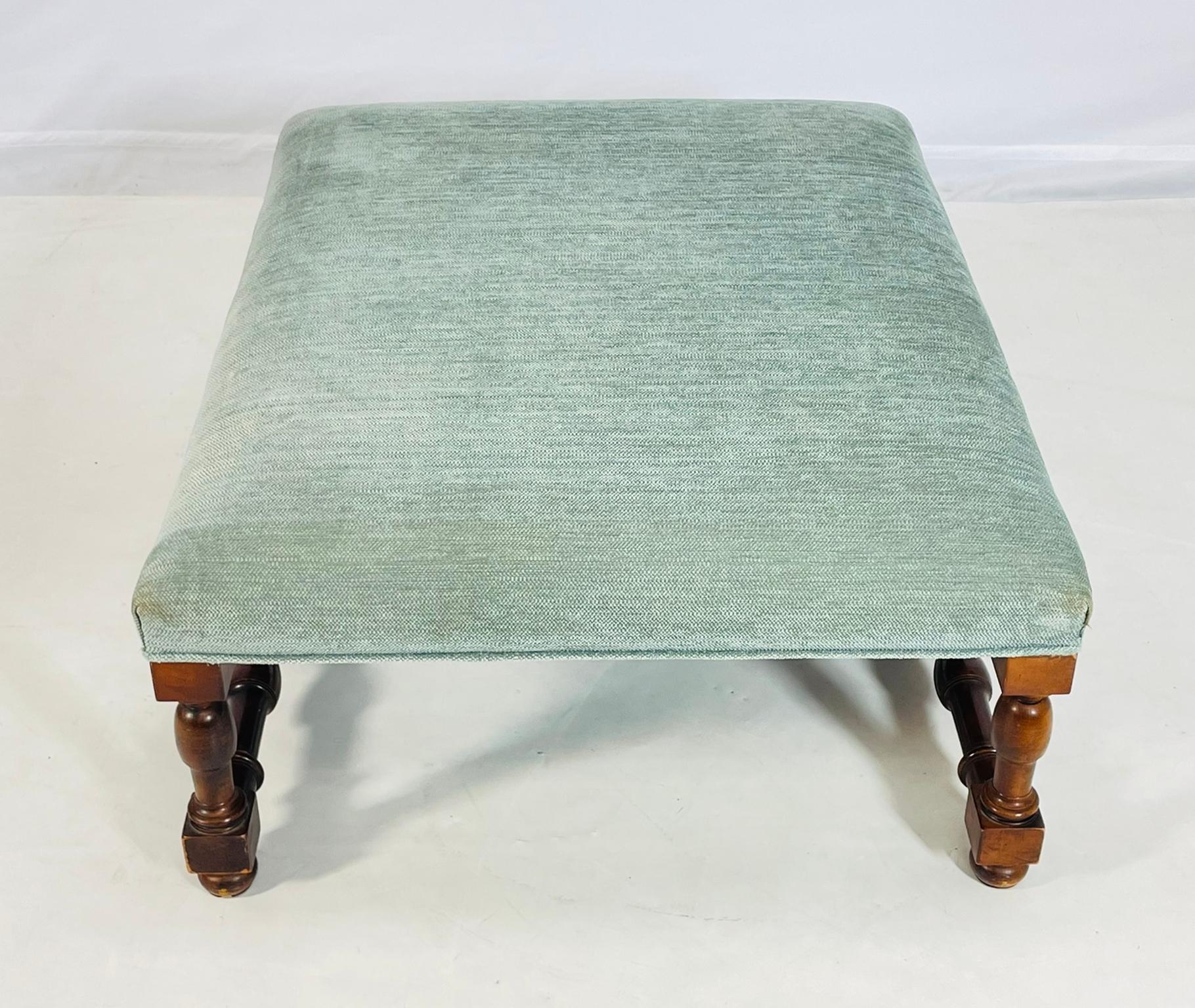 A refined ottoman/bench by Polo Ralph Lauren, featuring a finely turned hardwood frame with rich patina and a stretcher base for added stability and visual interest. The rectangular seat is upholstered in a soft, textured green fabric, offering a