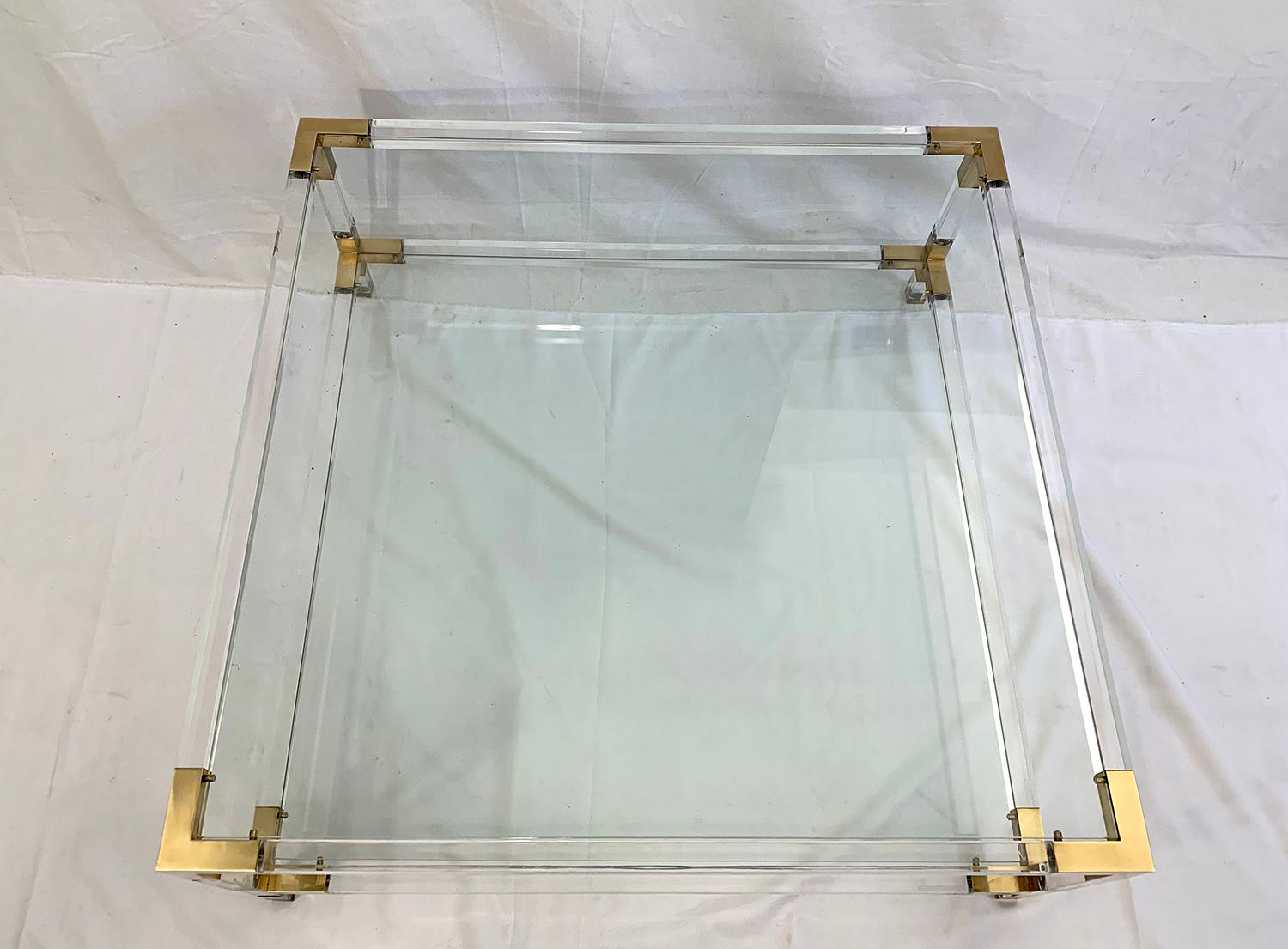 Large coffee table with two glass shelves in the style of Charles Hollis or Maison Jansen, The windows are removable and the frame is made of Lucite with corners in polished brass. Manufacture, circa 1970.

The glass can be replaced for 200