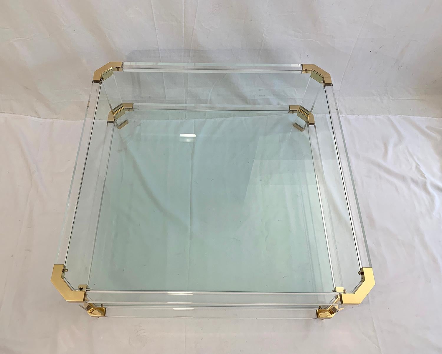 Large coffee table with two glass shelves in the style of Charles Hollis or Maison Jansen, The windows are removable and the frame is made of lucite with corners in polished brass. Manufacture around 1970.


Grande table de salon avec deux étagères