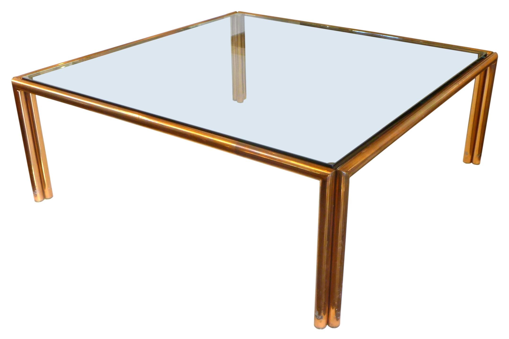 A wonderful, large square coffee table of copper-tube and glass. A simple yet elegant form of impressive, ample proportion and classic materials; a welded, heavy-stock copper tube frame cradling a nearly 4' square, original ¾