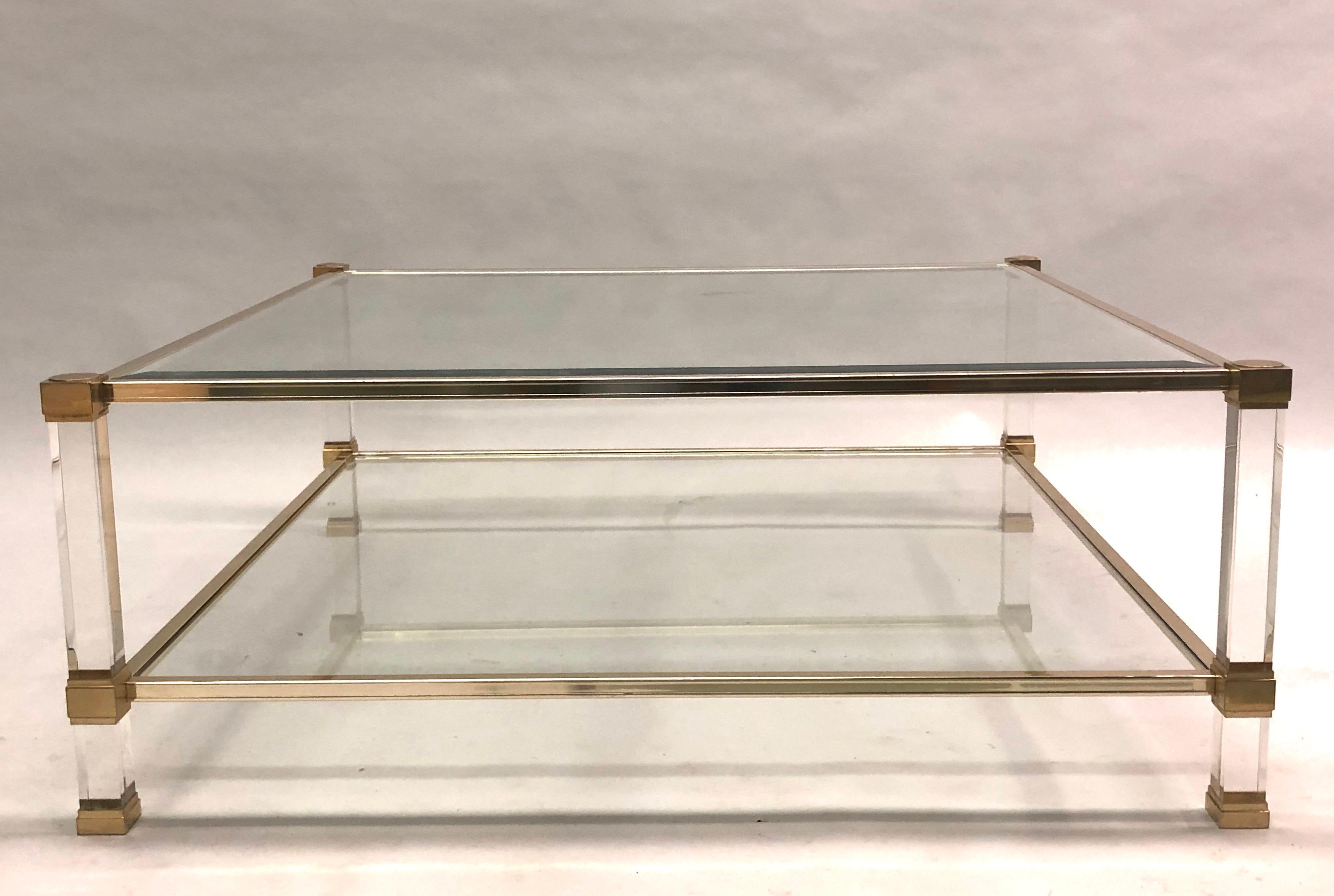 A large, square, French Mid-Century Modern, double level cocktail table in Lucite and brass by Pierre Vandel. The square form of this table is rare and highly desirable for chic look and practical applications.