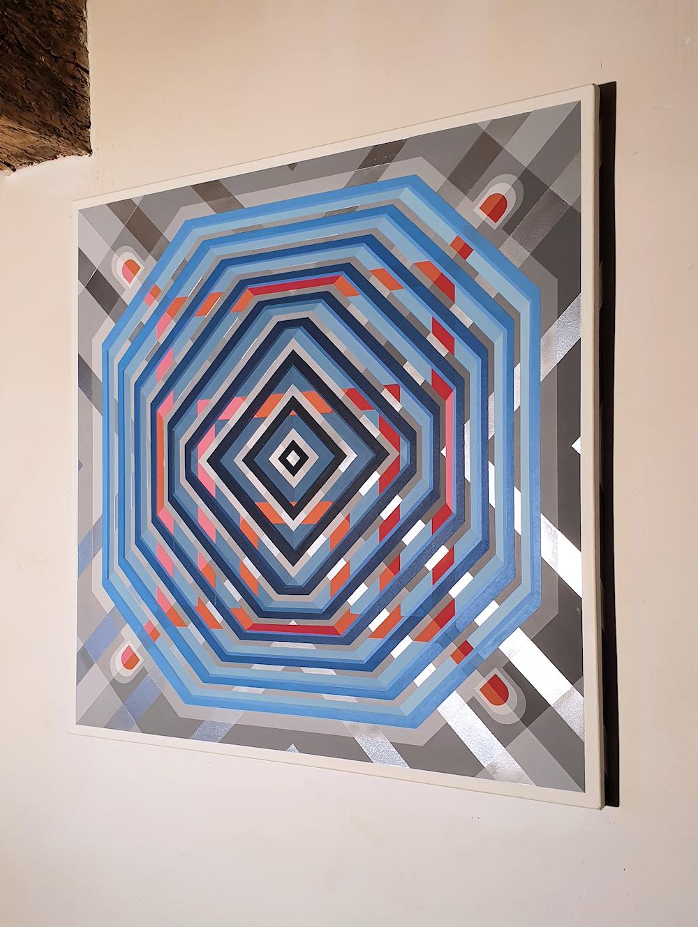 Contemporary acrylic painting on canvas, large square shape, by French artist Philippe Delhom, 2020.
The abstract geometric pattern, with blue, red and orange colors change through the reflections of the silver back-ground. The geometric design