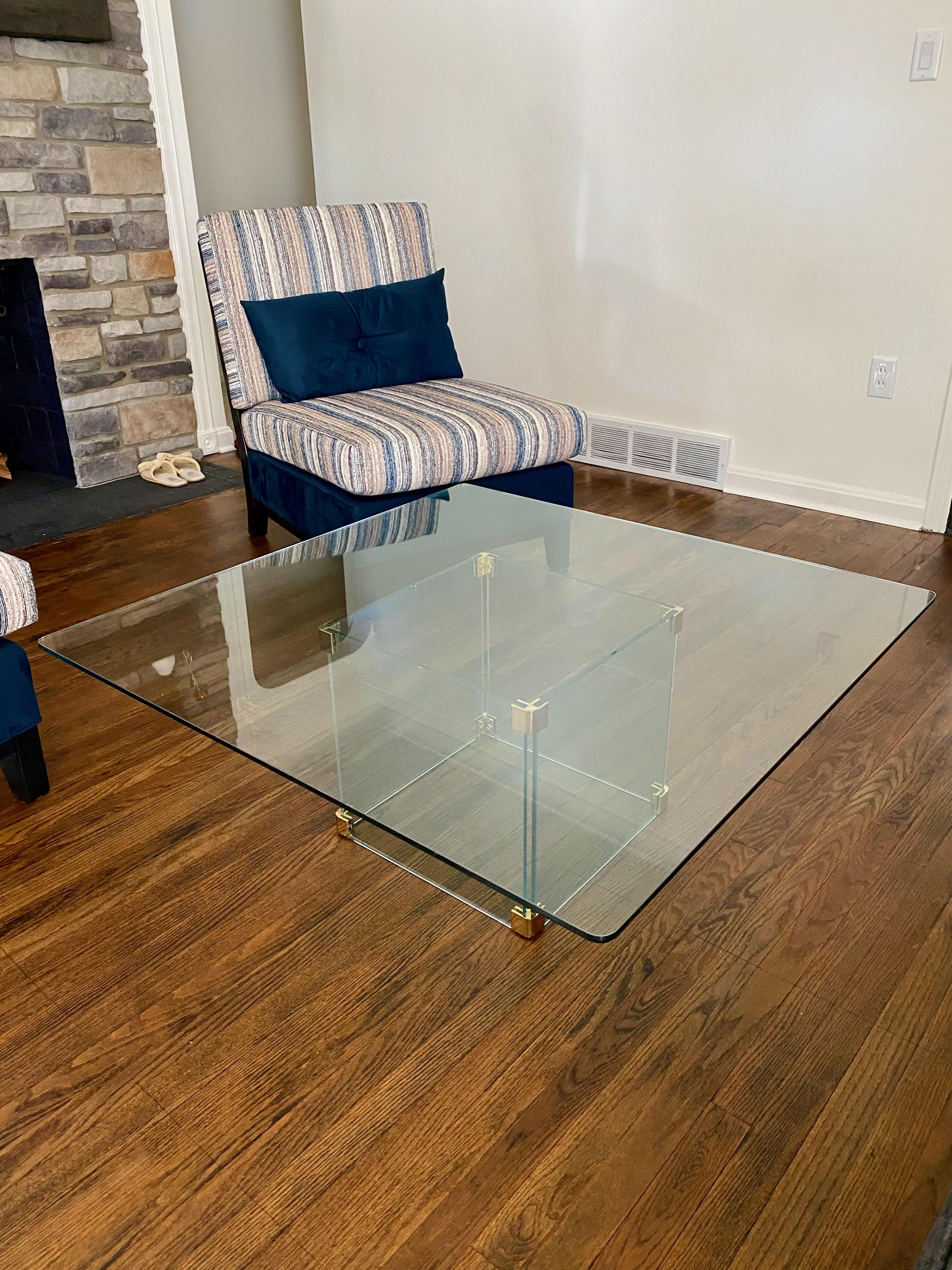 Magnifique grande table basse en verre avec des supports en laiton. Pas de copeaux dans le verre. Plateau en verre amovible, les séparations en caoutchouc doivent être remplacées, mais l'ensemble est en excellent état.