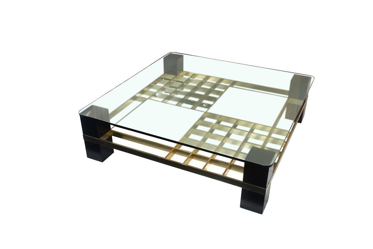 1960s French two-tier glass top coffee table with black ebonized legs and panels and bronze grid pattern decorative details.

