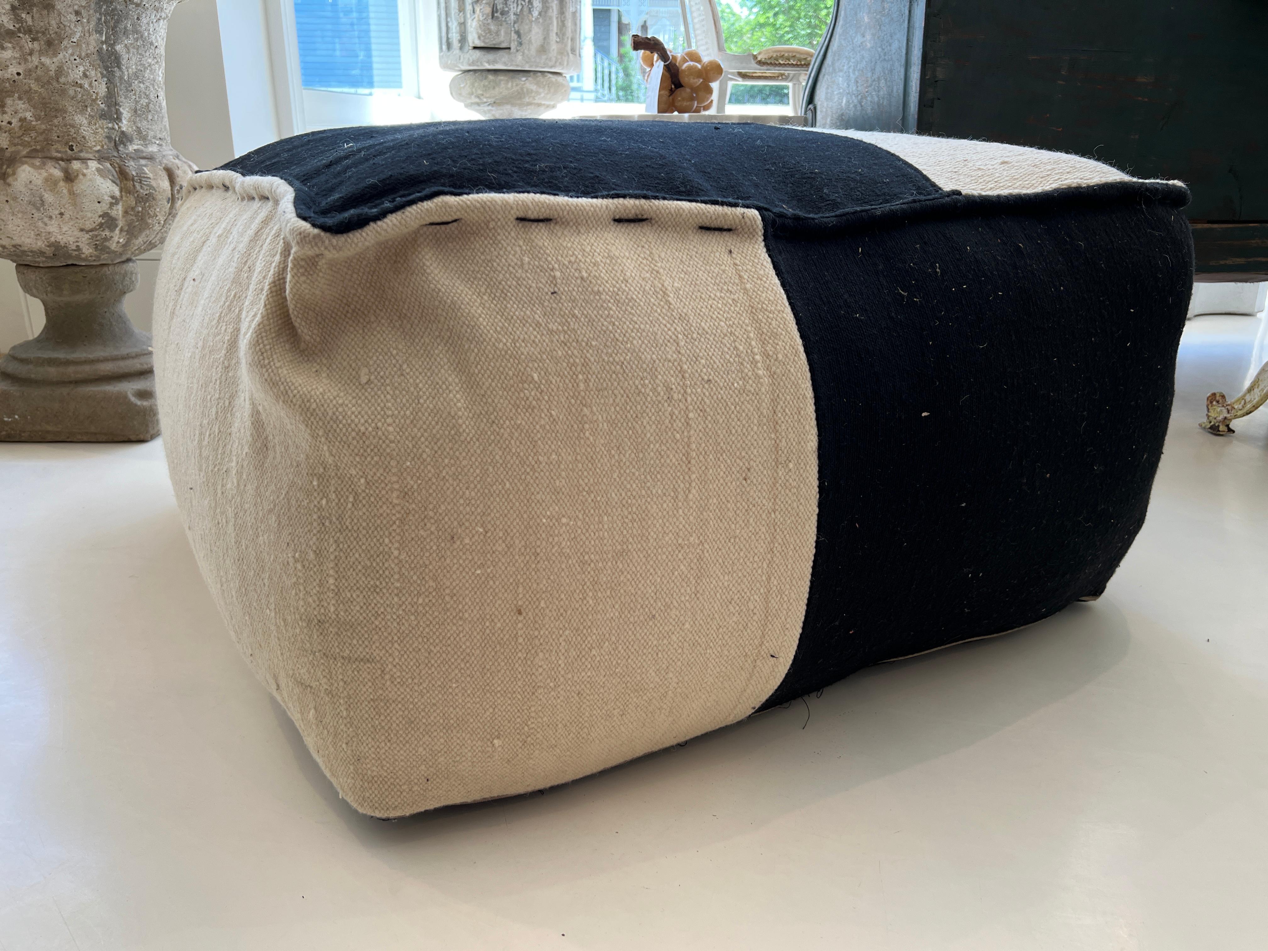 Very large footstool or pouf made of rustically woven wool.