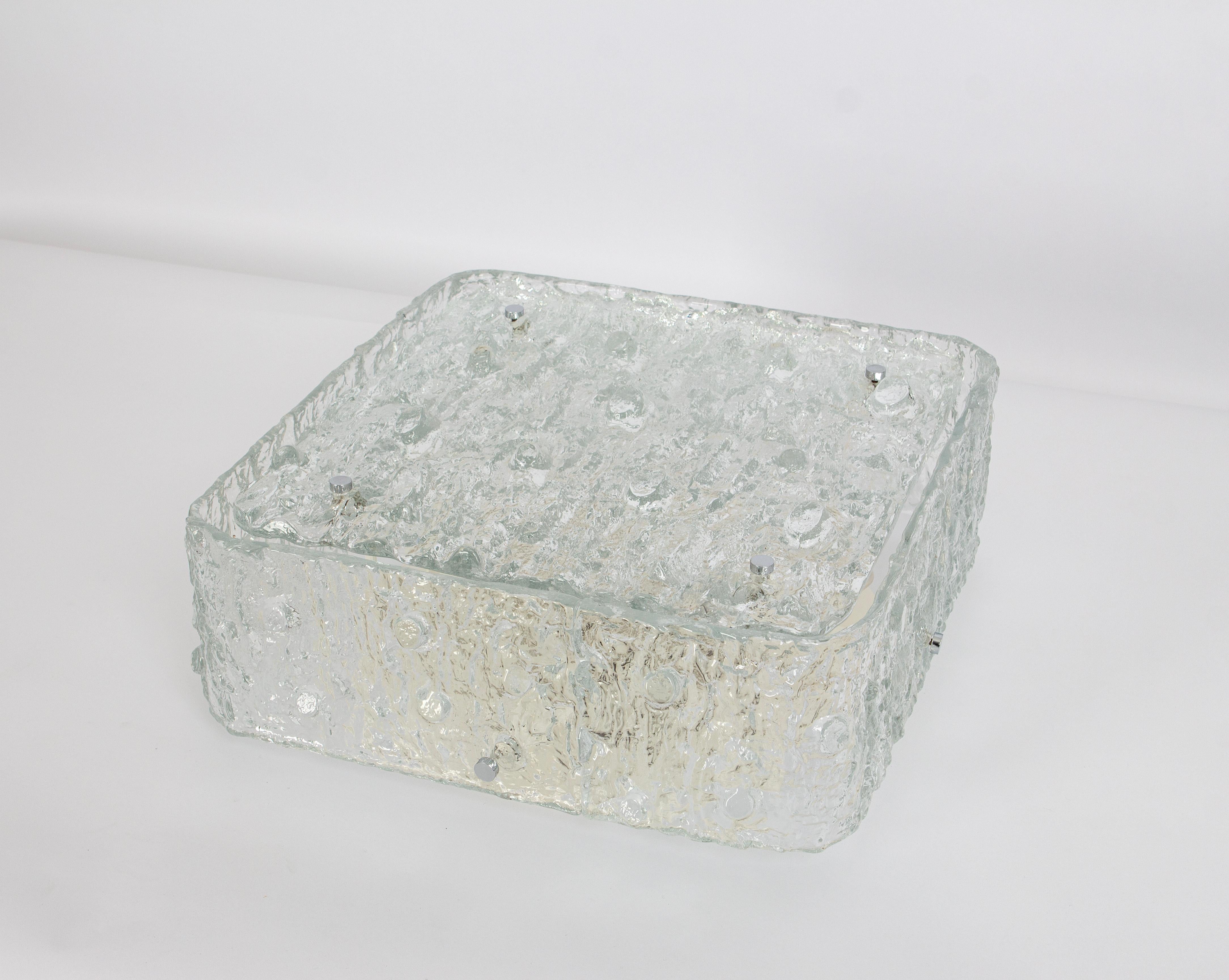 A wonderful Large square Murano ice glass flush mount light made in Germany in the 1970s.
Thickly textured ice glass fixture on a white metal base with eight chrome holders.

Heavy quality and in very good condition. Cleaned, well-wired and ready to