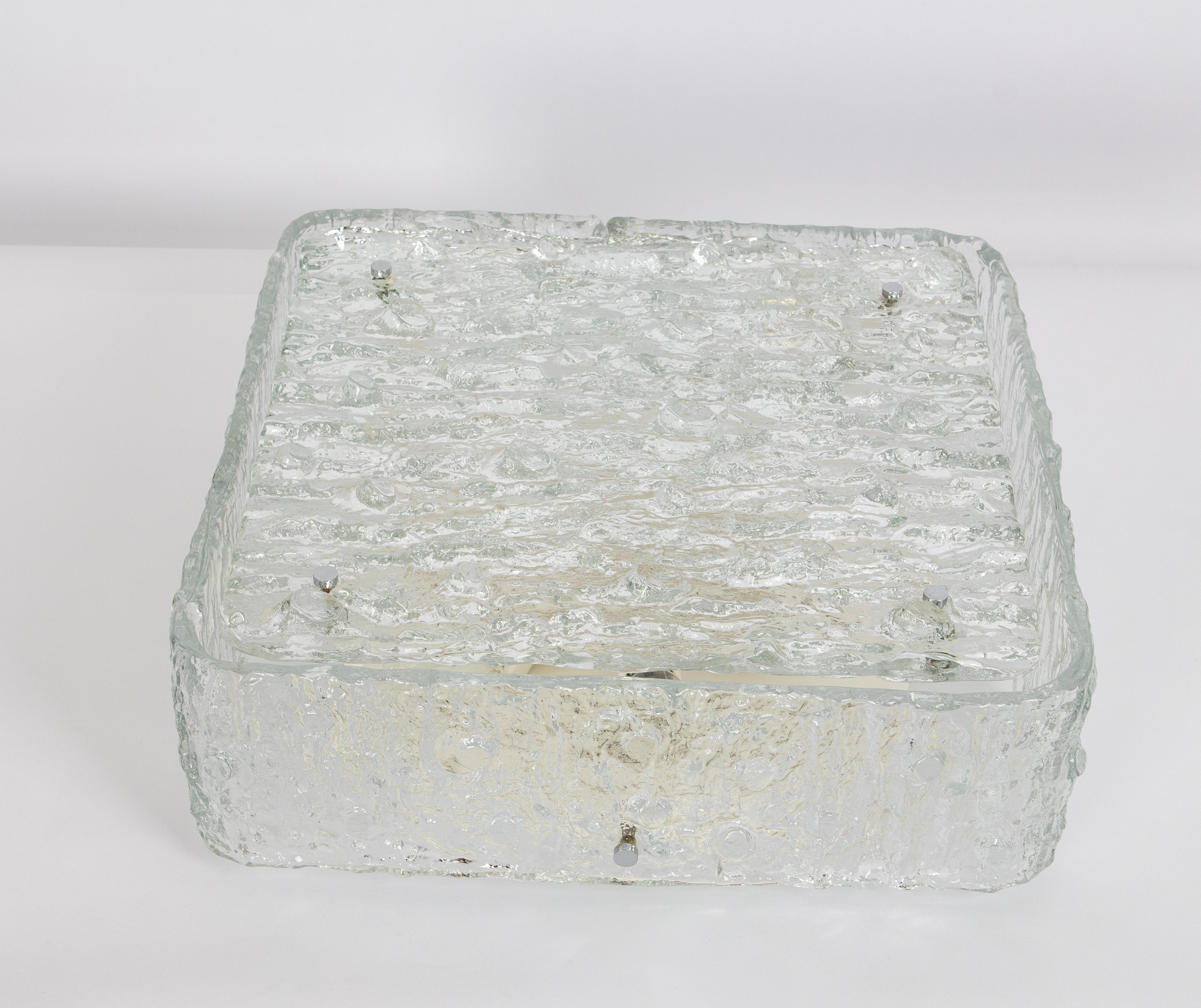 A wonderful Large square Murano ice glass flush mount light made in Germany in the 1970s.
Thickly textured ice glass fixture on a white metal base with eight chrome holders.

Heavy quality and in very good condition. Cleaned, well-wired and ready to