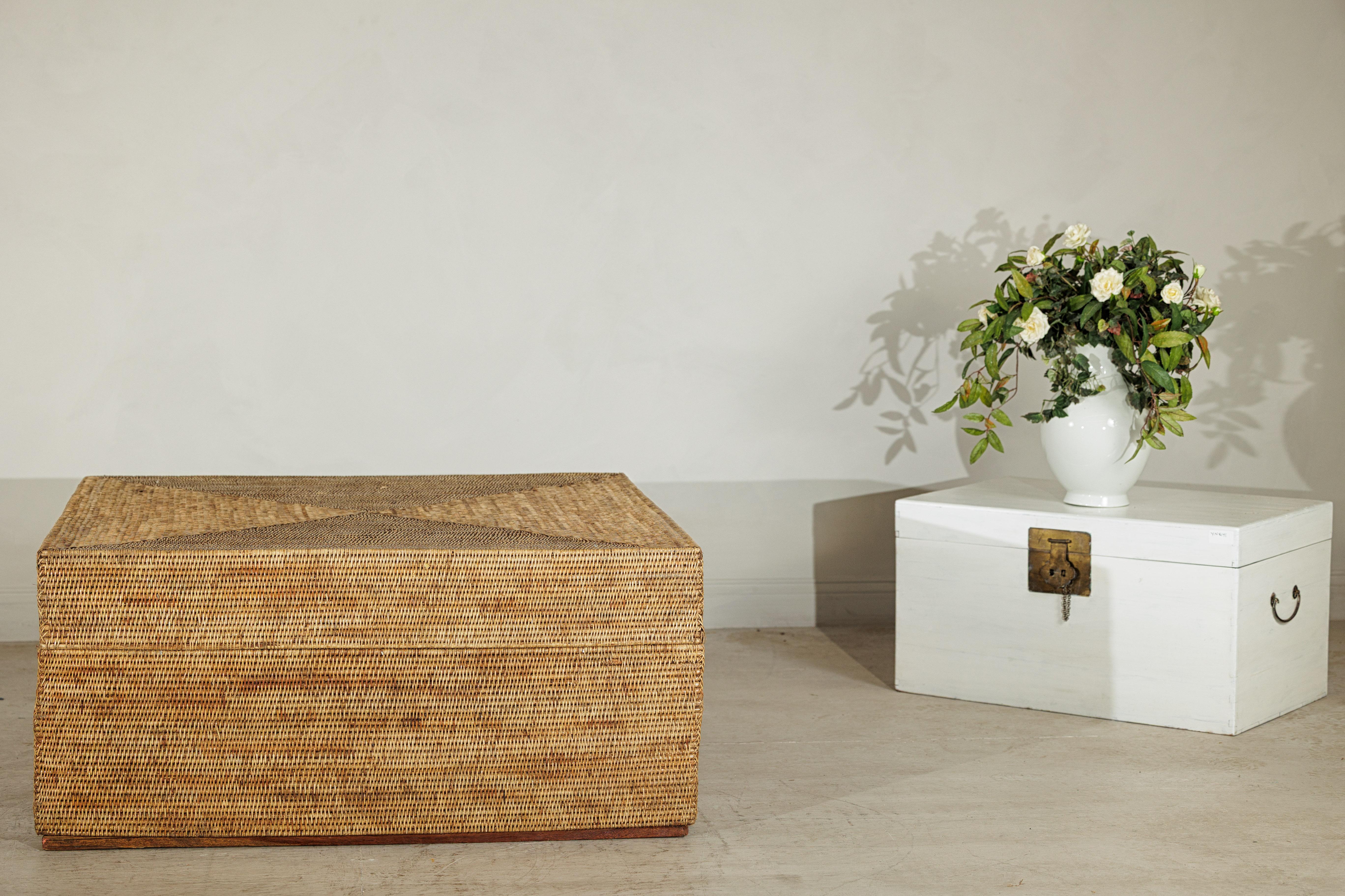 Esta gran mesa de centro cuadrada de ratán combina un diseño práctico con una textura natural y una elegancia discreta. Los paneles de ratán tejido a mano crean una superficie cálida y orgánica con sutiles variaciones tonales, dispuestas en un