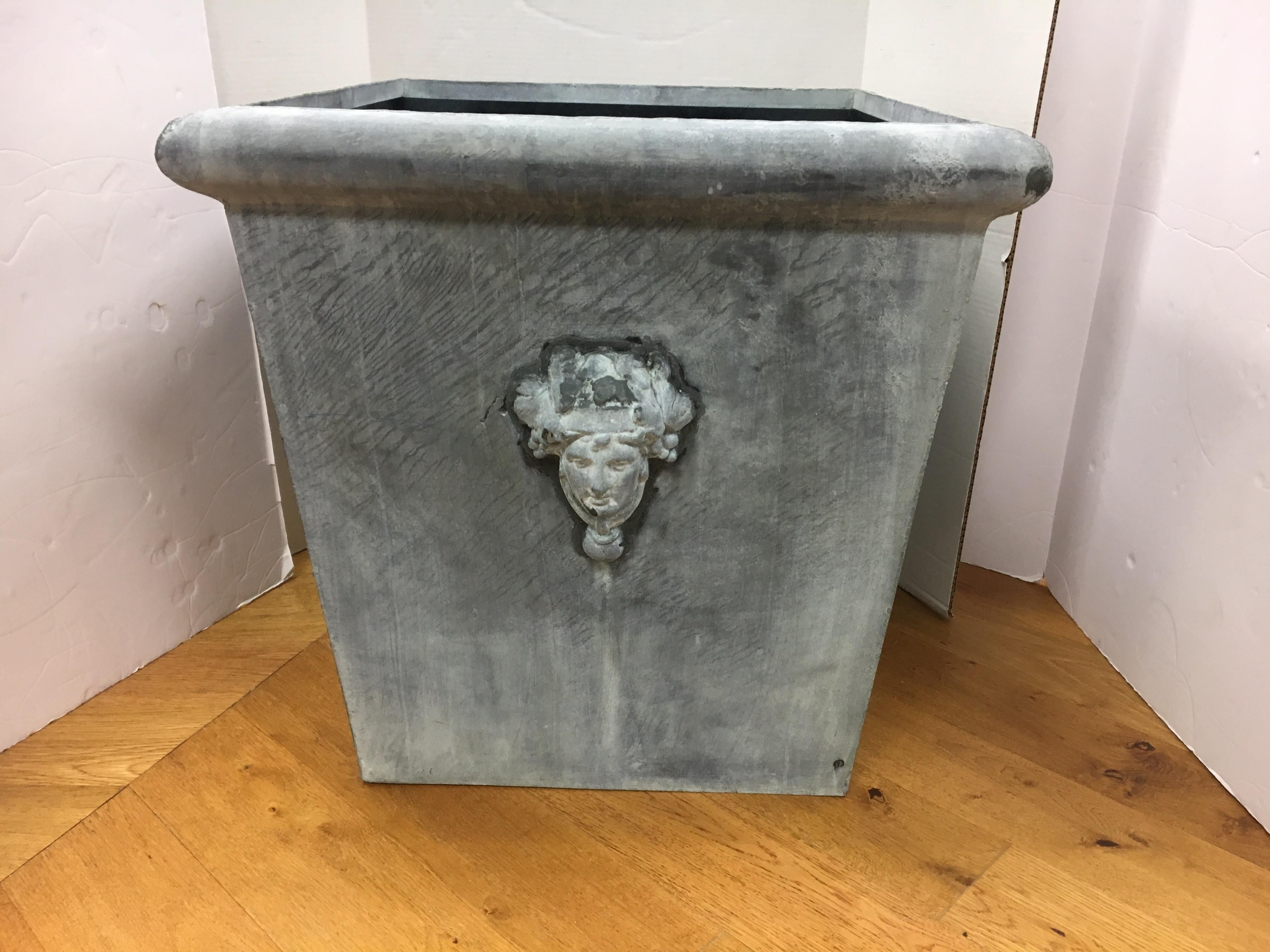 Large square zinc planter with Greek figural head on one side. Has pre-drilled hole for drainage. Very unusual.