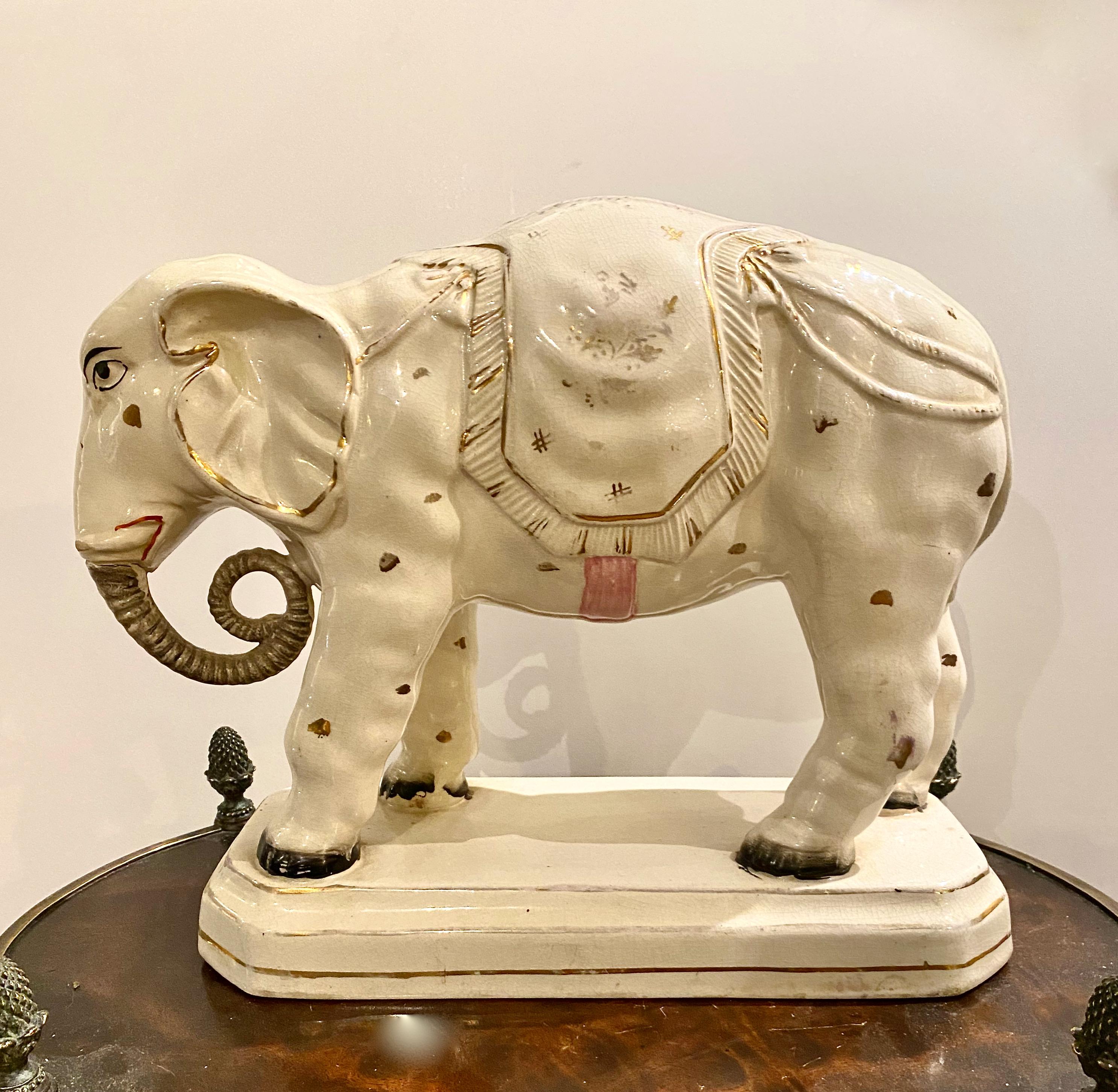 This is a very rare and large Staffordshire figure of an Indian elephant on a plinth, dressed in its traditional drapings. The elephant dates to c. 1880 and is in overall very good condition. There is minor patina and a bit of crazing which is