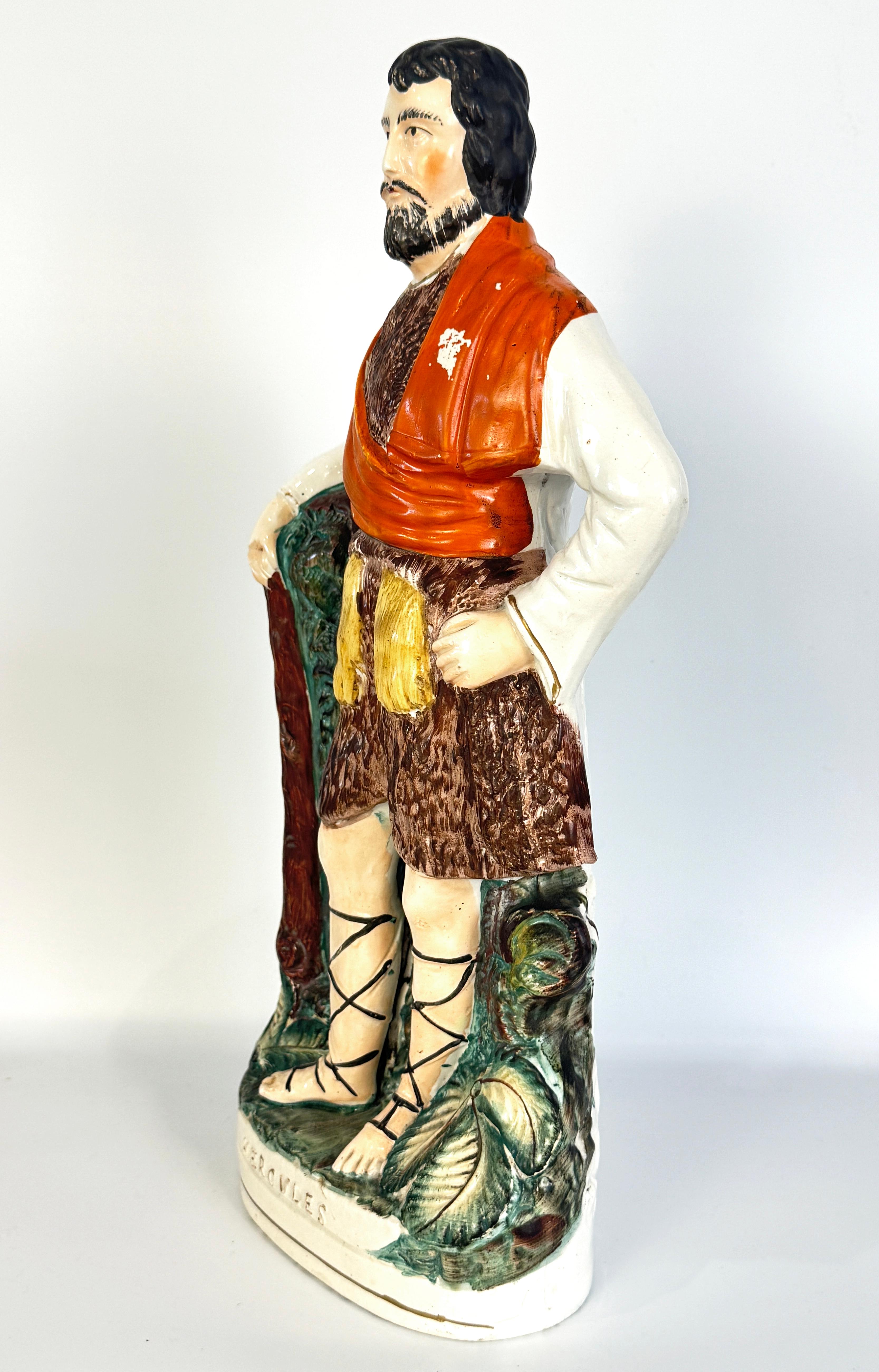 Grande figure d'Hercule en poterie du Staffordshire, avec nom sur la base. Cette figurine de taille significative représente Hercule avec sa massue, se tenant nonchalamment debout dans un décor de bocage classique du Staffordshire. L'échelle de la