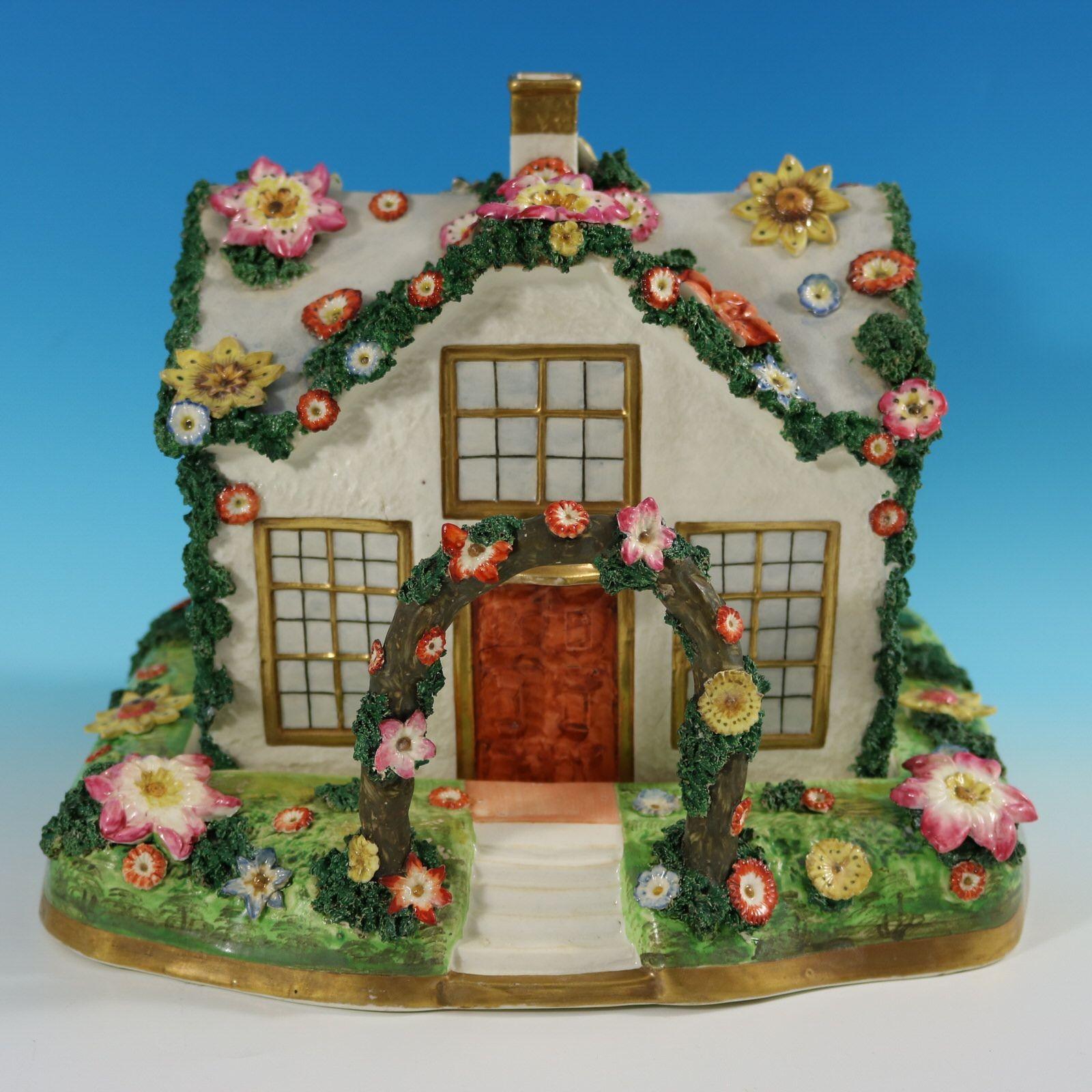 Staffordshire Pottery porcellaneous pastille burner which features a country cottage embellished with flowers. The house has stairs leading up to the front door, with an arbour arching overhead. The lid lifts off, revealing the pastille holder,