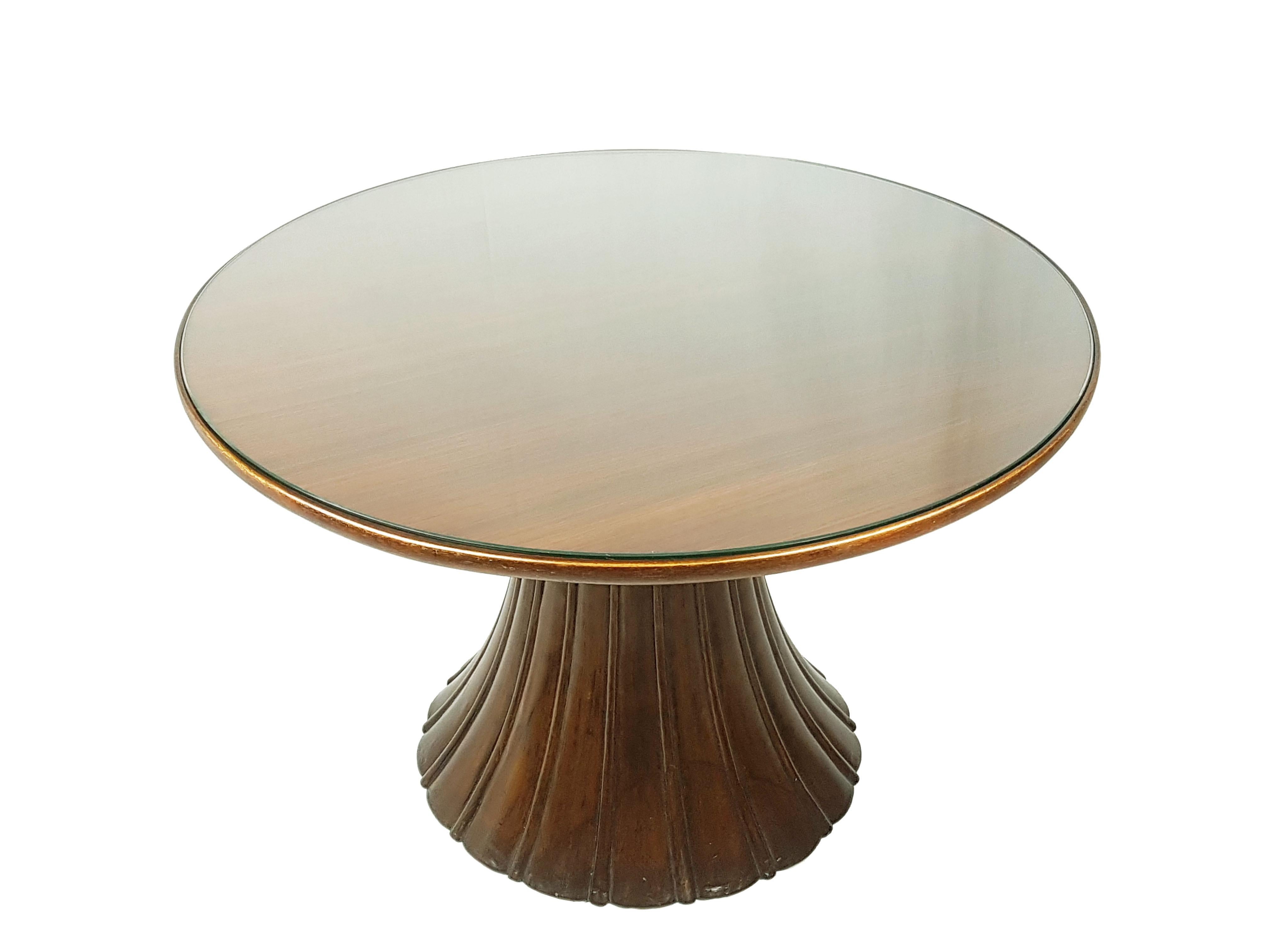 Fine et rare table basse attribuée à Guglielmo Ulrich. Cette belle table a été fabriquée en Italie vers les années 1940 en bois massif, teinté et poli, avec un plateau rond en verre. La structure de la base est massive et sculpturale et contraste