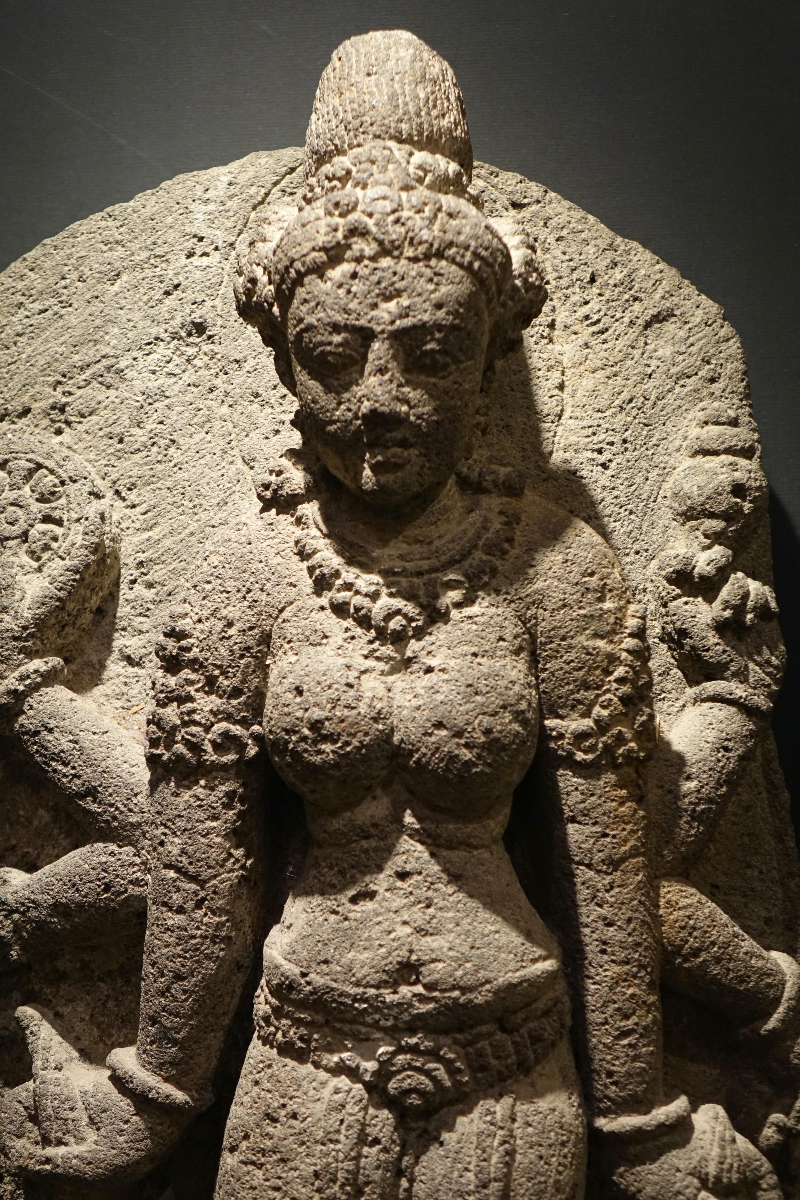 Large standing goddess holding various attributes with her six arms resting on a recumbent buffalo, accompanied by a worshipper. 
Height 72 cm.