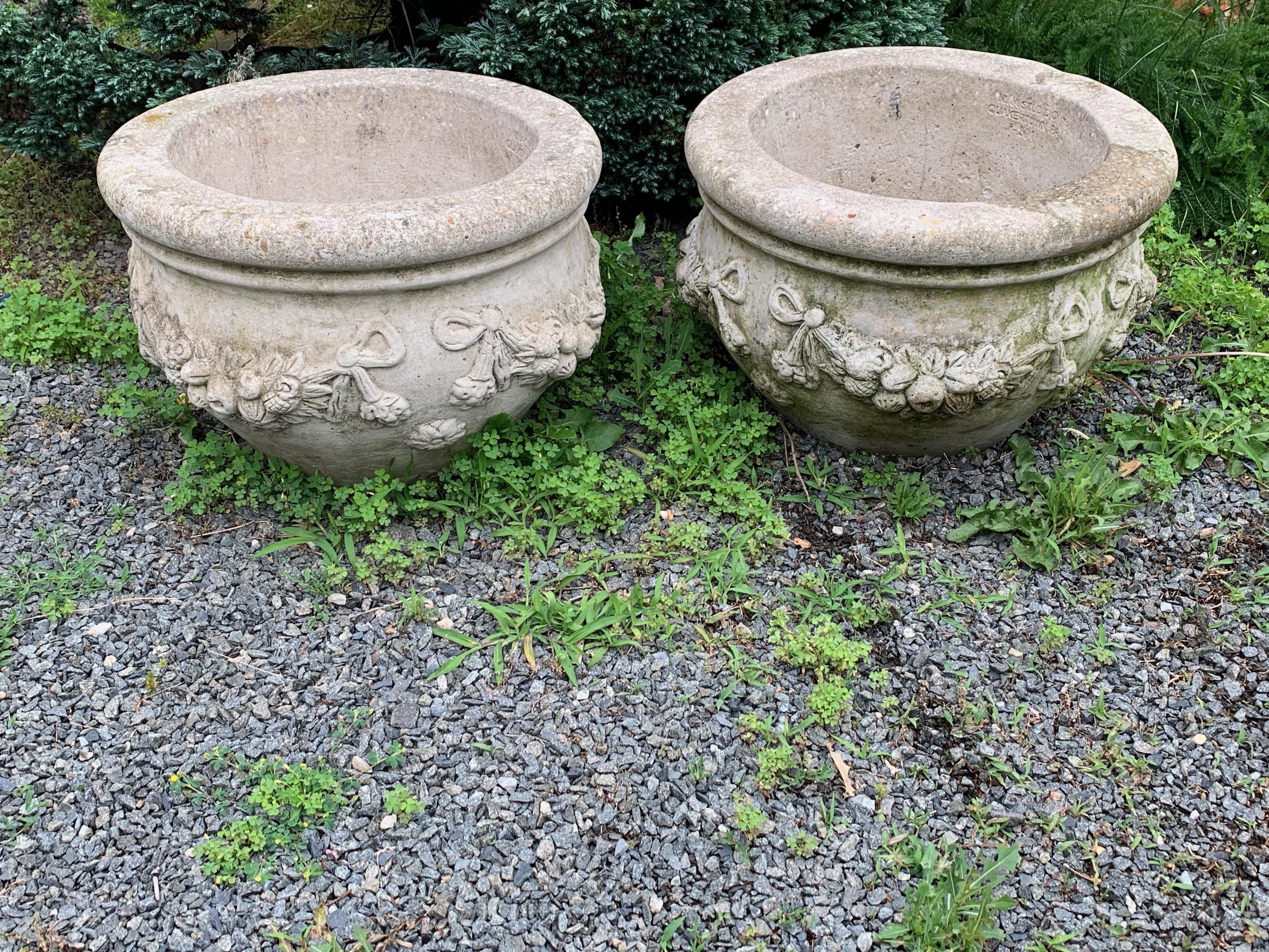 Lovely large pair of cast stone cement round planters by Nina Studio, Quakertown PA, having garland decoration with fruit and flowers.