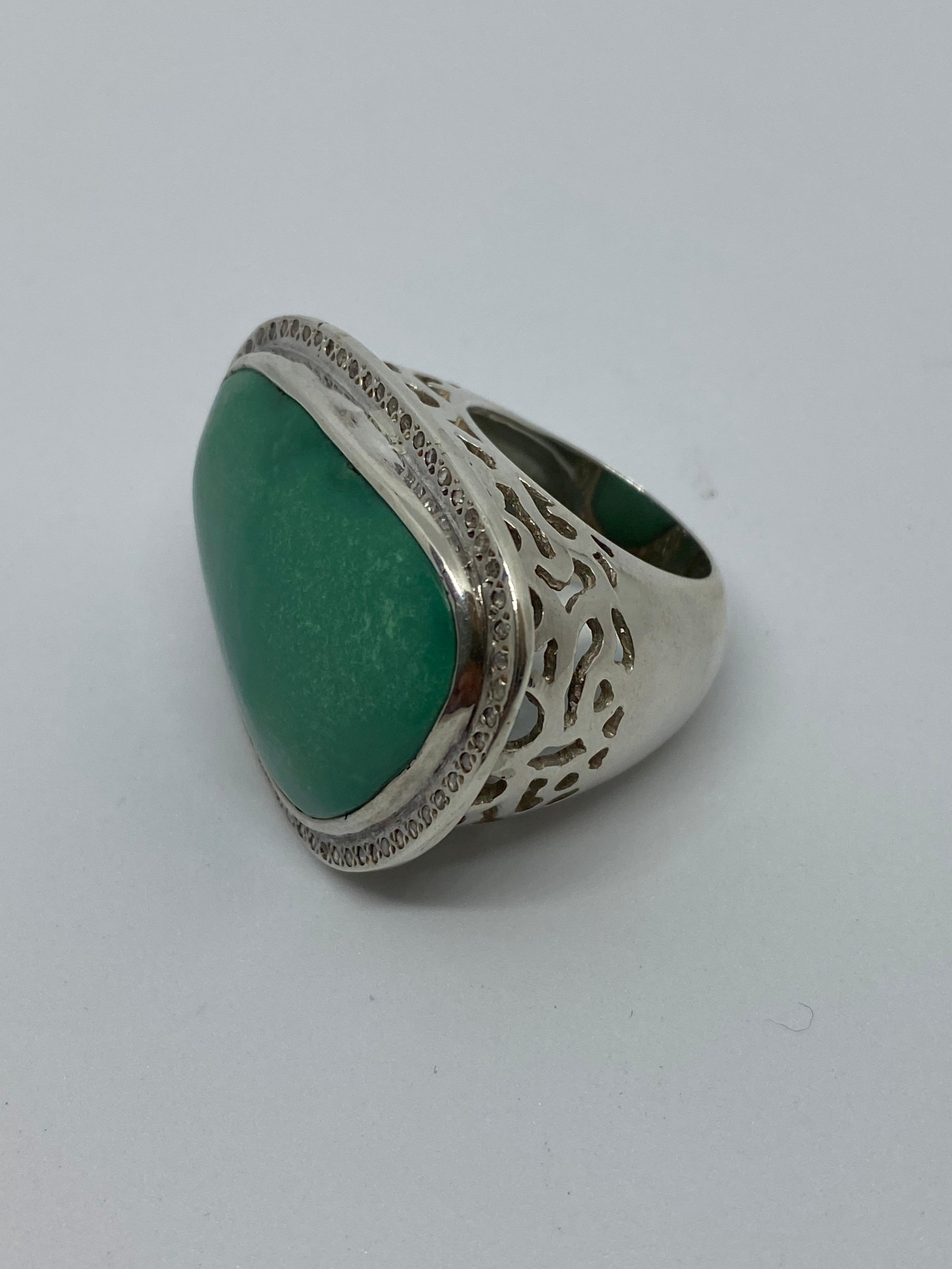 This is a very large free-formed Dyed Turquoise Ring that is bezel set with tiny Rose Cut Diamonds around the bezel. It sits on an open gallery cut out of Sterling Silver. Fits a Finger size 7.5 US size. Measures 1.25 inches in length and  1.50