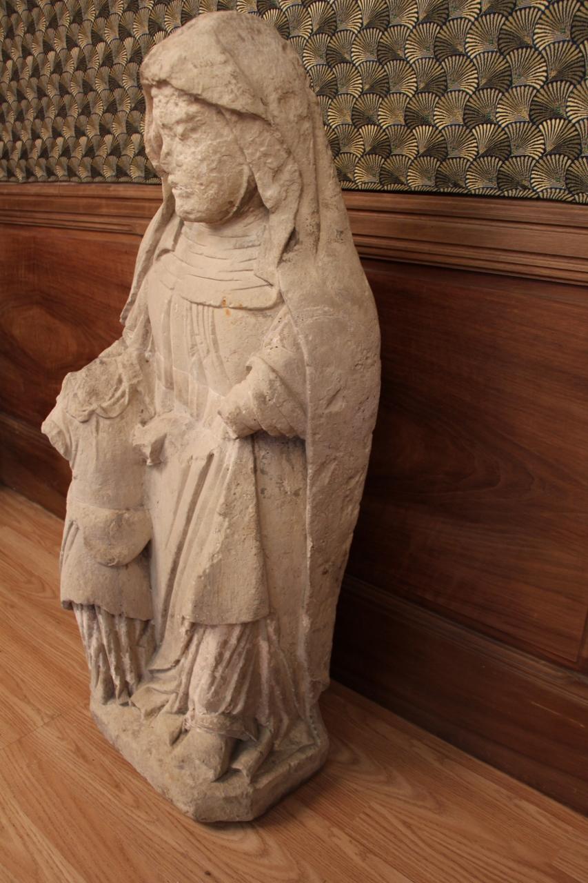 large statue of saint anne in limestone, from the 15th century has suffered the ravages of time, several parts are missing, but the statue remains legible old restorations.
