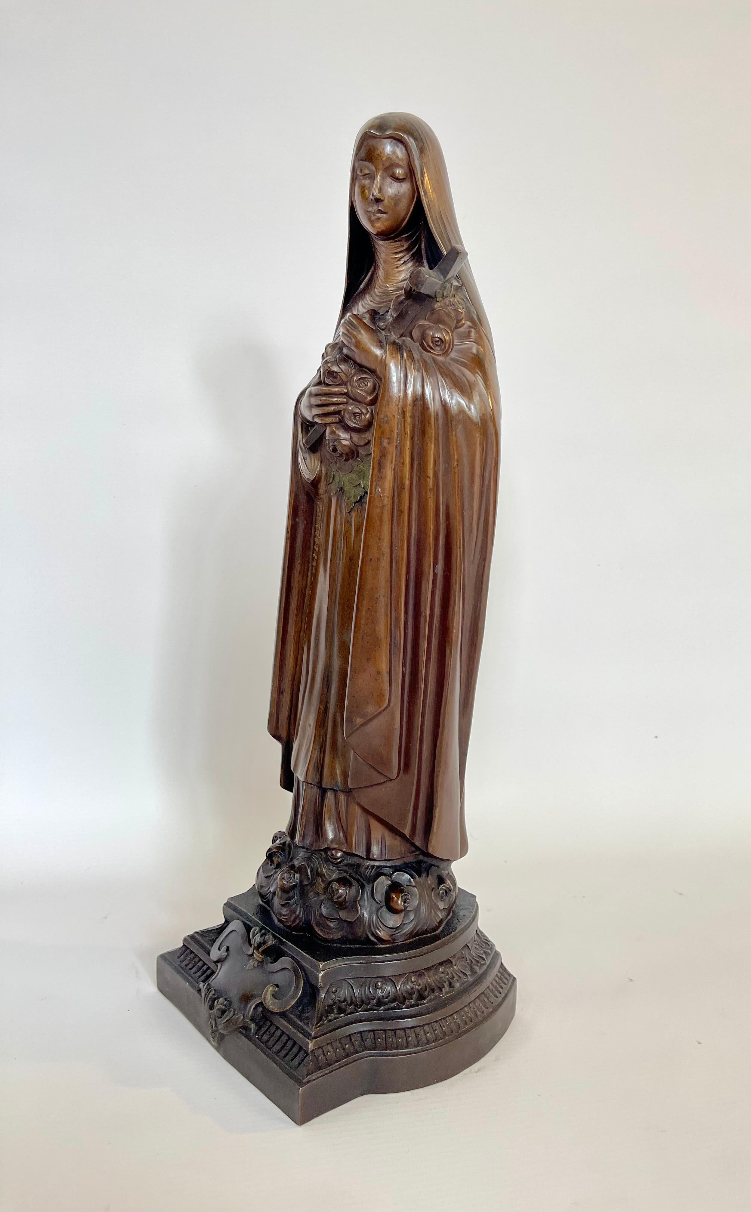 A large statue from the late 19th to early 20th century depicting the Holy Virgin with the cross of Jesus in her arms. She rests on a promontory adorned with flowers. The statue is made of spelter. It is signed on the back 'Ch. Raphael Peyre.' This