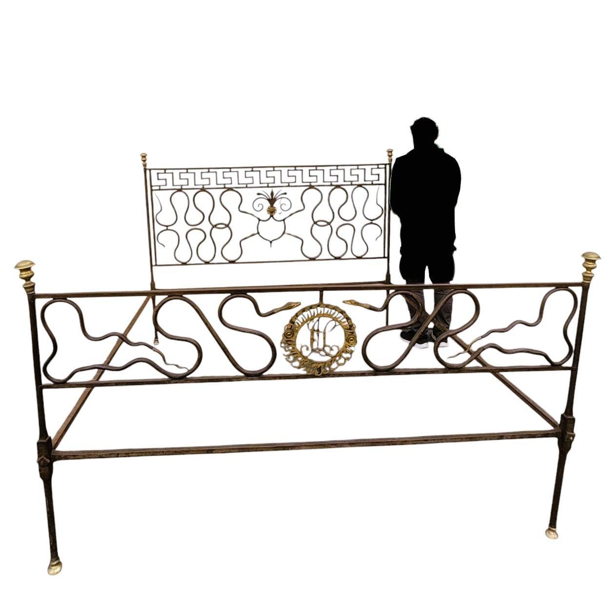 Exceptional steel bed, with a brown/grey and gold patina, decorated with interlacing ending in snake heads and tails. 

The initials of the person for whom this bed was intended are in a coat of arms in the center of the footboard; the same initials