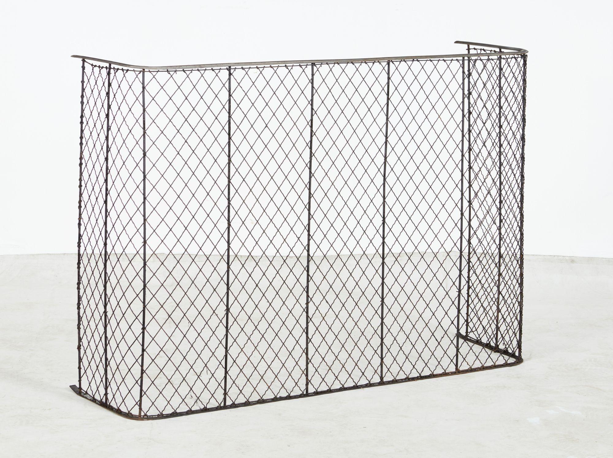 A fireplace or nursery guard with steel top rail having wide diamond mesh supported by iron bars and a curved lower iron rail. Nursery guards were designed to keep children and dogs away from the fire, and sometimes to as clothing or towel hangers.