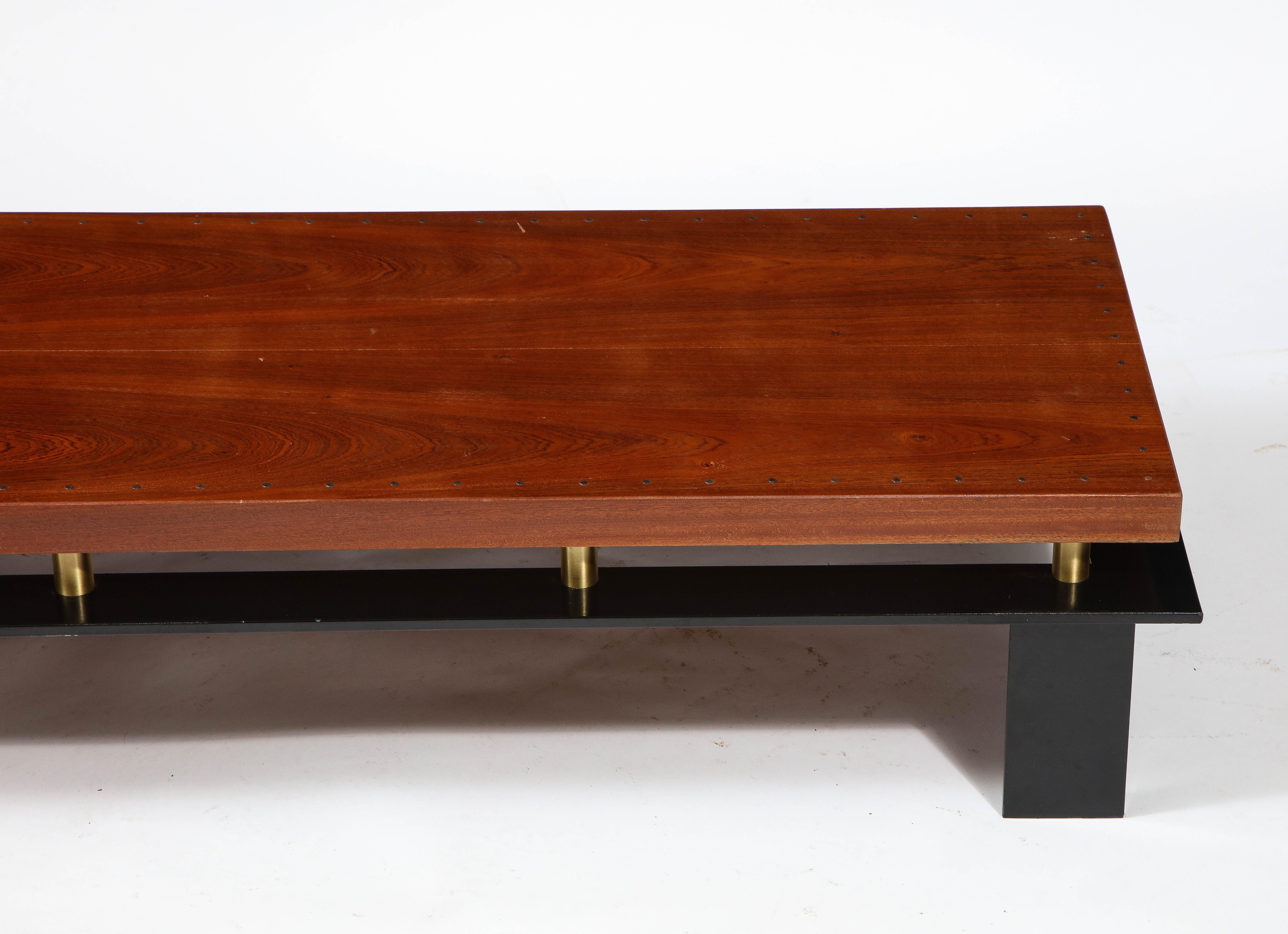 Large coffee table with solid walnut top with nailhead details on a solid black enameled steel base with brass stands.