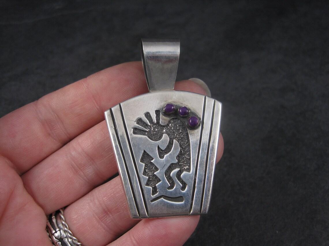 This sterling silver Kokopelli pendant is signed Mexico, 925 and has the makers id.

It measures apx 2.5 inches from the top of the bail to the bottom.

It is accented by 3 purple sugilite stones.

It is in excellent condition.